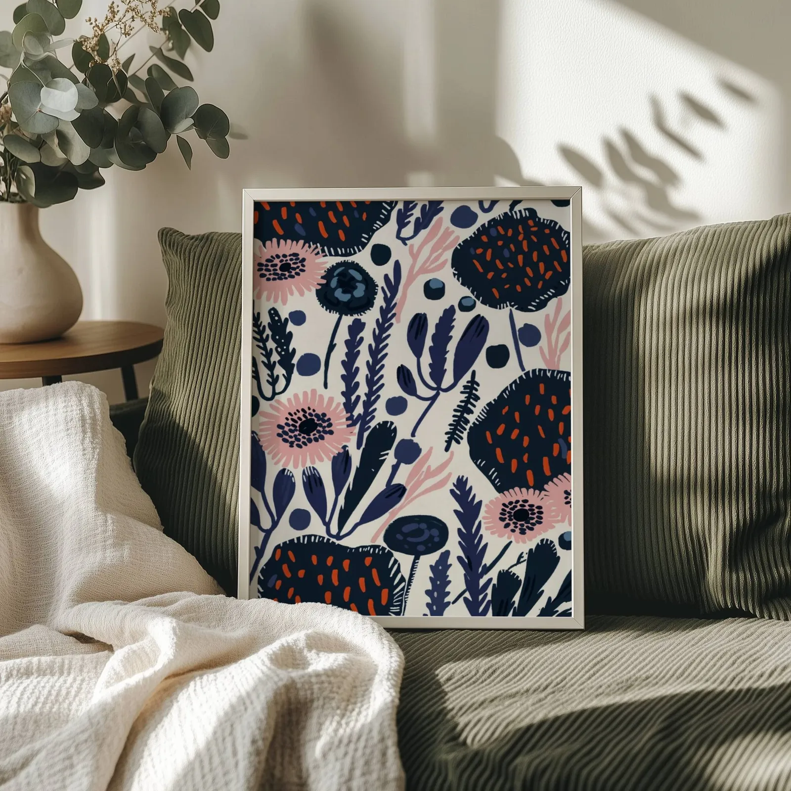 navy blue floral botanical wall art, propped on an olive corduroy sofa beside a eucalyptus vase