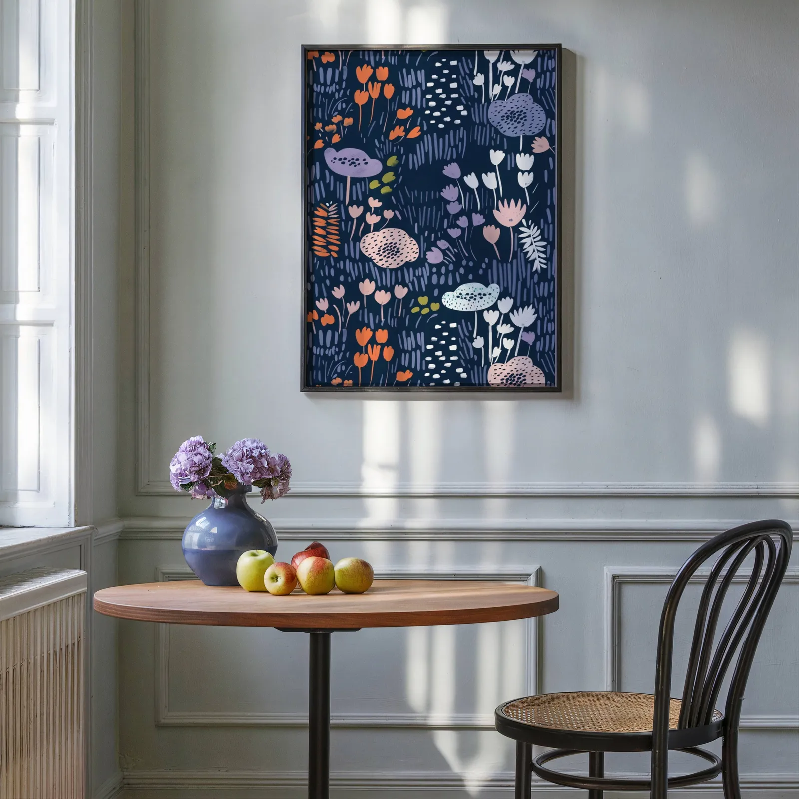navy floral botanical wall art print, above a round wooden table with apples and a blue vase