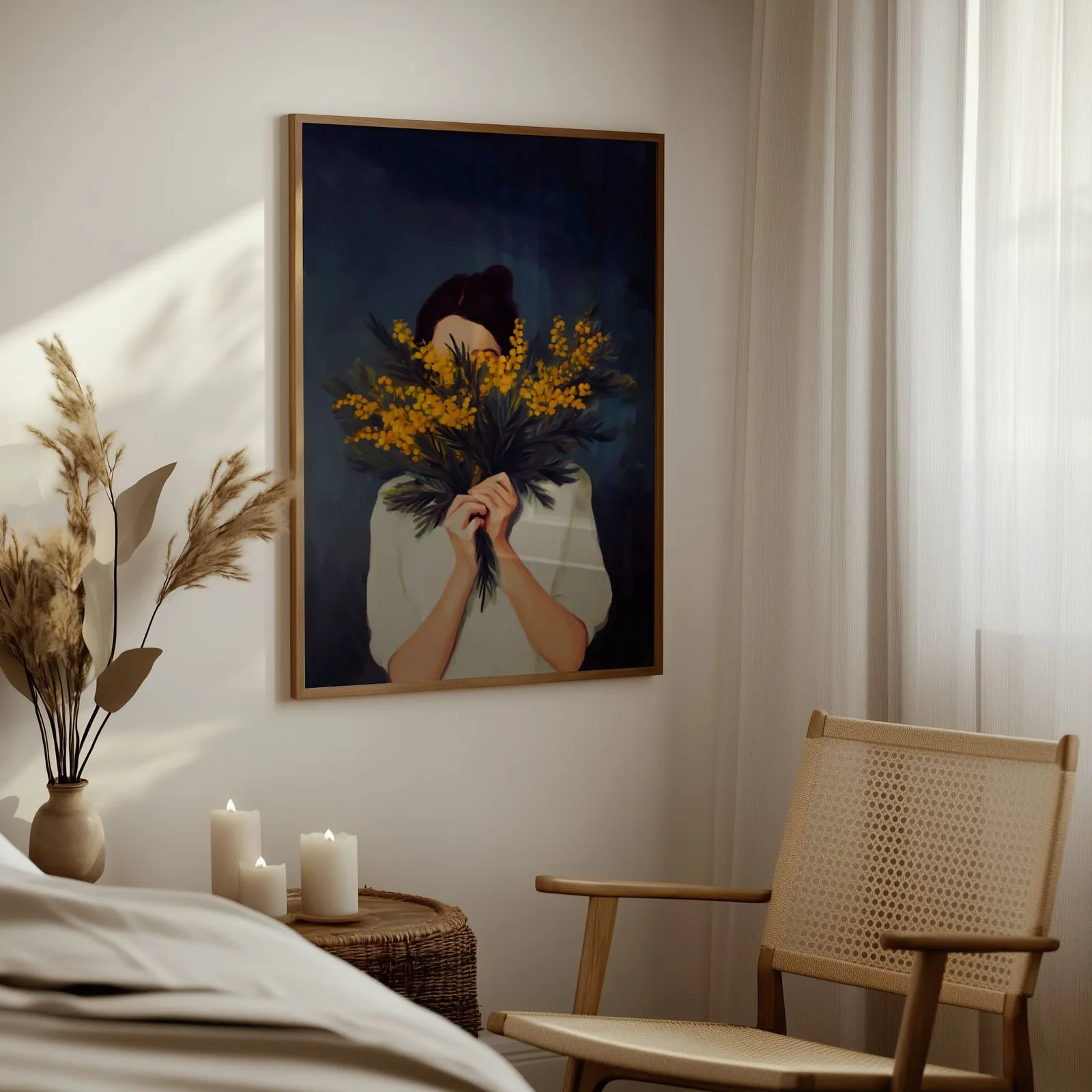woman with yellow mimosa flowers wall art, above a woven side table with lit candles and pampas grass