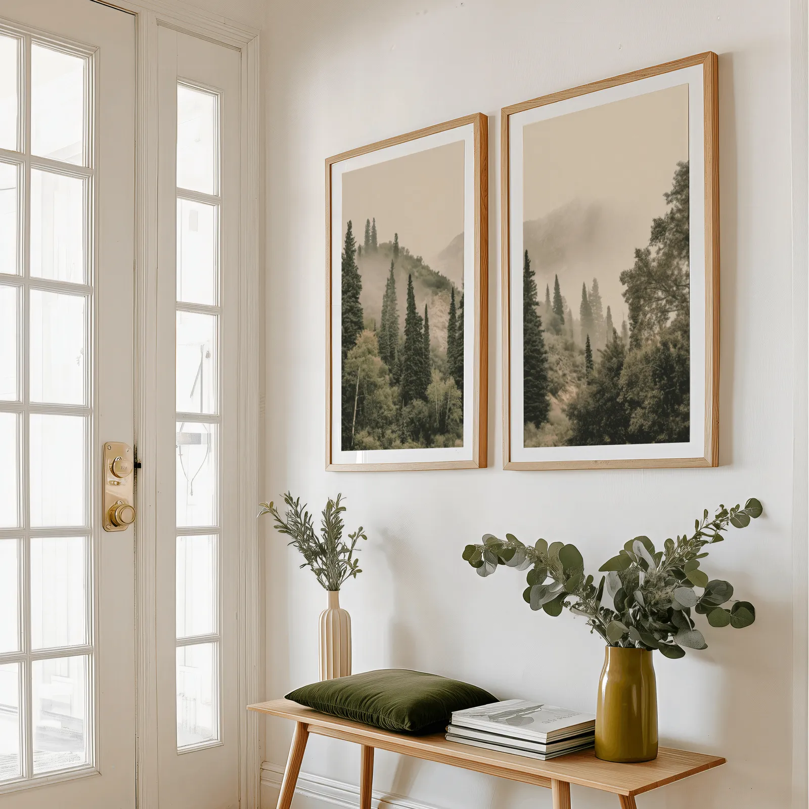misty forest wall art set of two pine hillside prints, above a wooden bench with eucalyptus stems and a green cushion