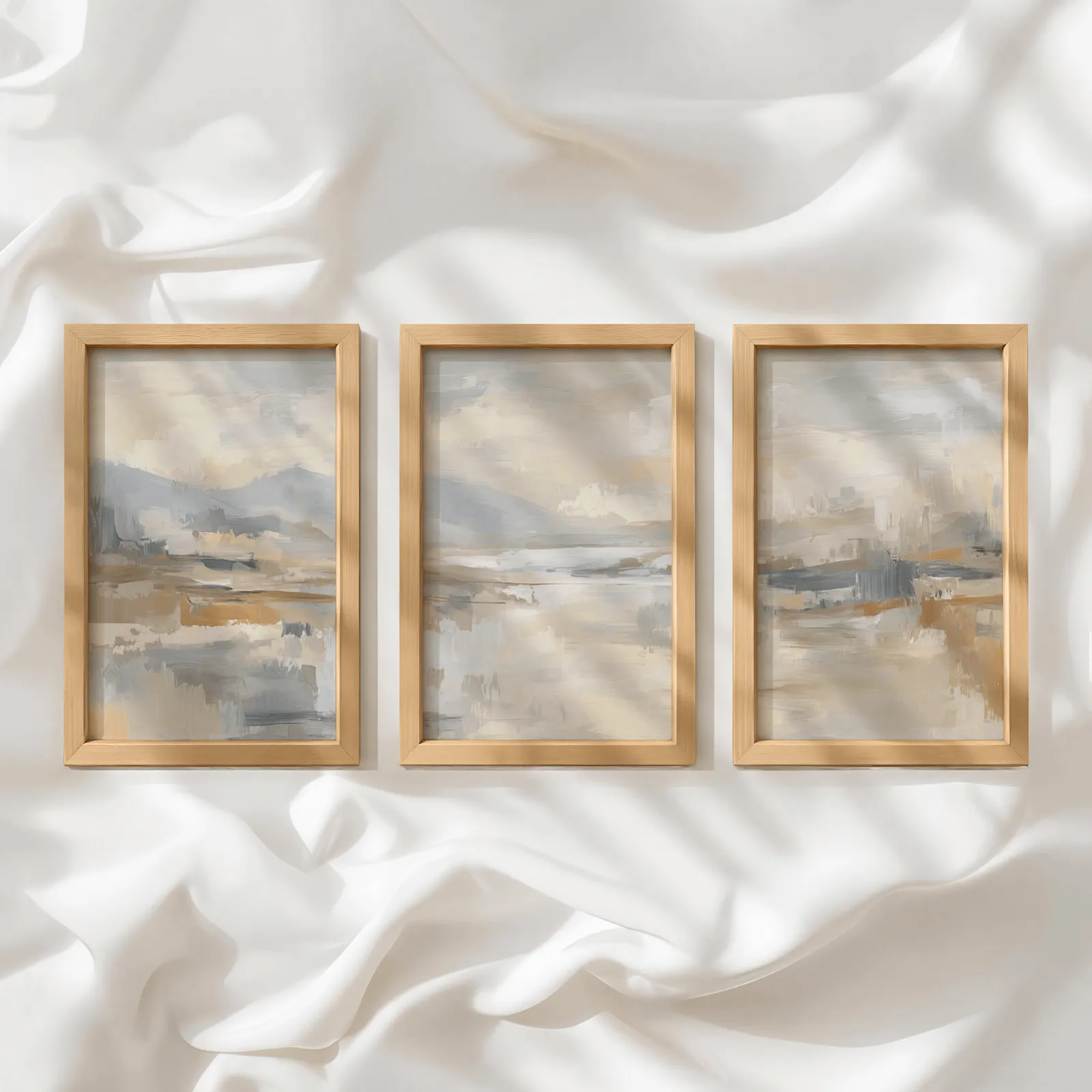 neutral abstract landscape wall art set of three, in a row atop rumpled white silky fabric