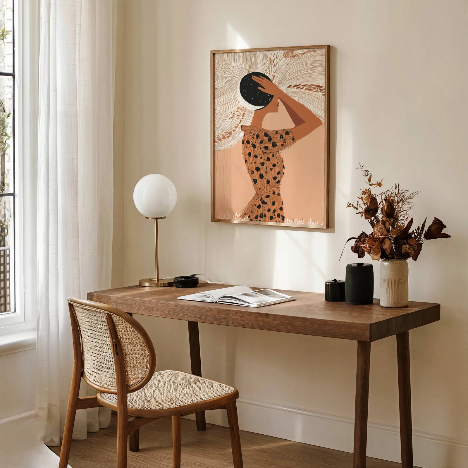 terracotta boho woman with moon wall art, above a wooden desk with a globe lamp and dried flowers
