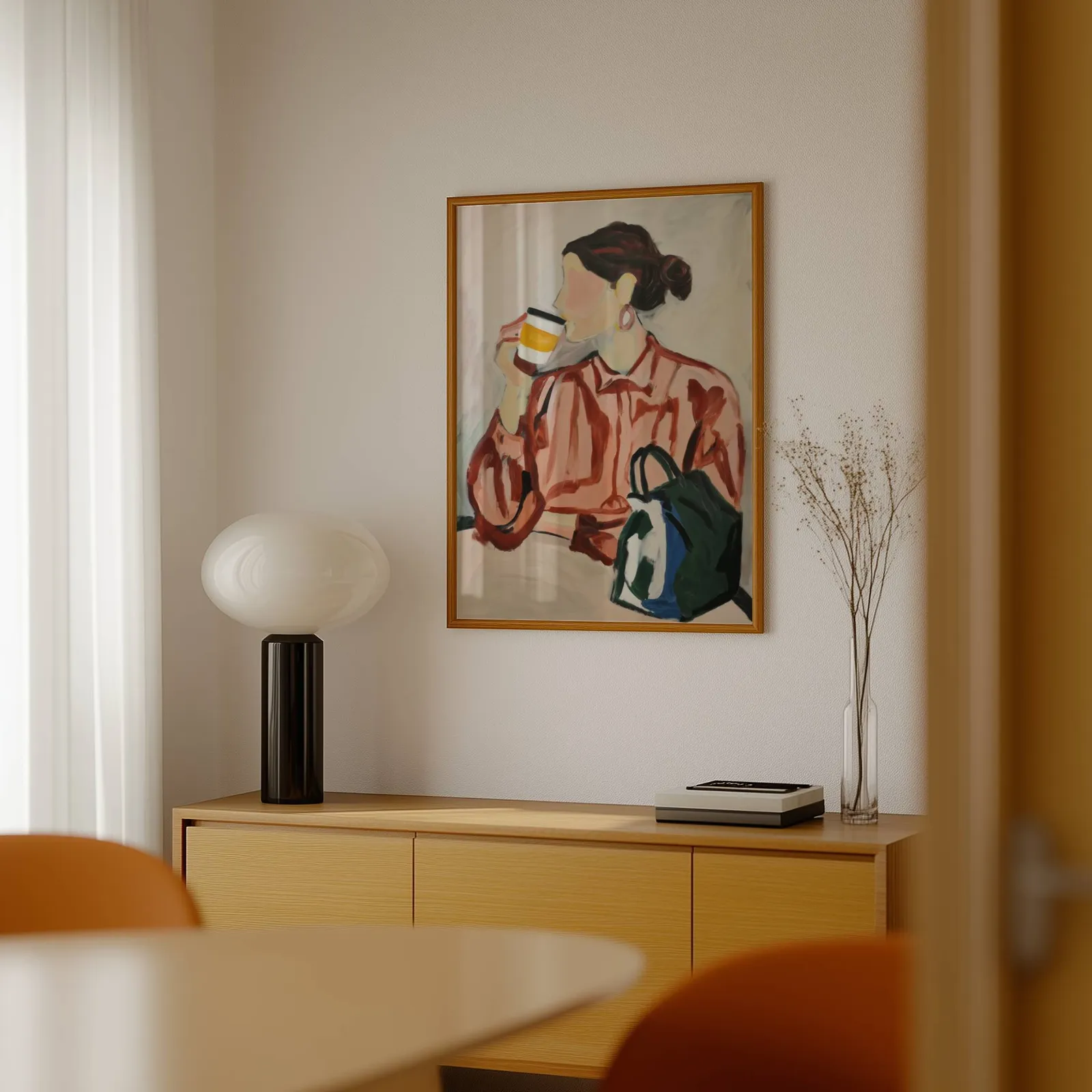 woman drinking coffee modern portrait wall art, above a light wood sideboard beside a bulbous black lamp