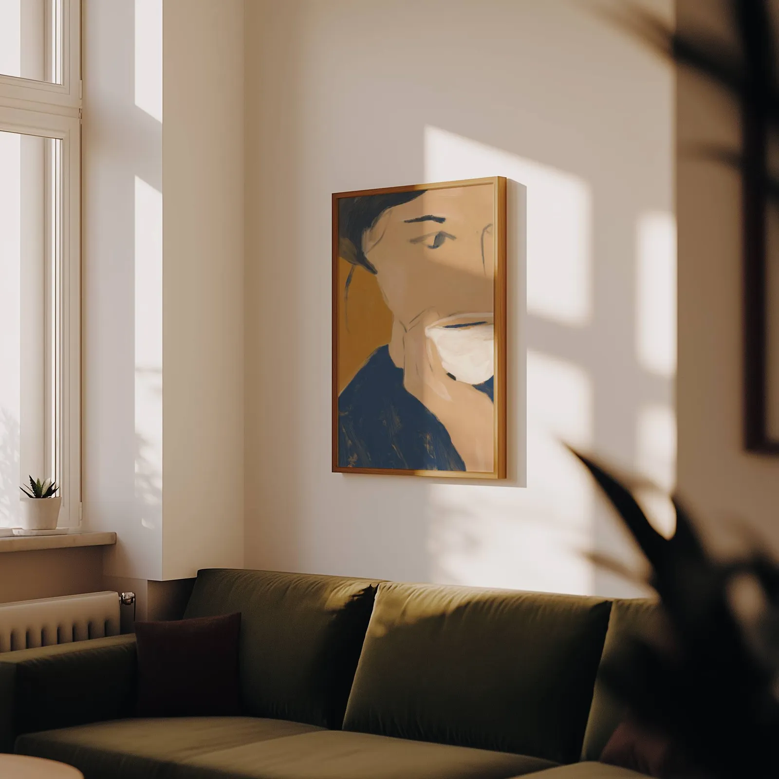 abstract portrait wall art with teacup in blue and orange, above an olive velvet sofa in raking afternoon light