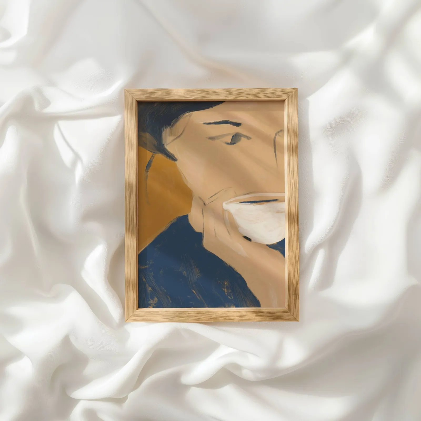 abstract portrait wall art with teacup in blue and orange, resting atop rumpled white silky fabric