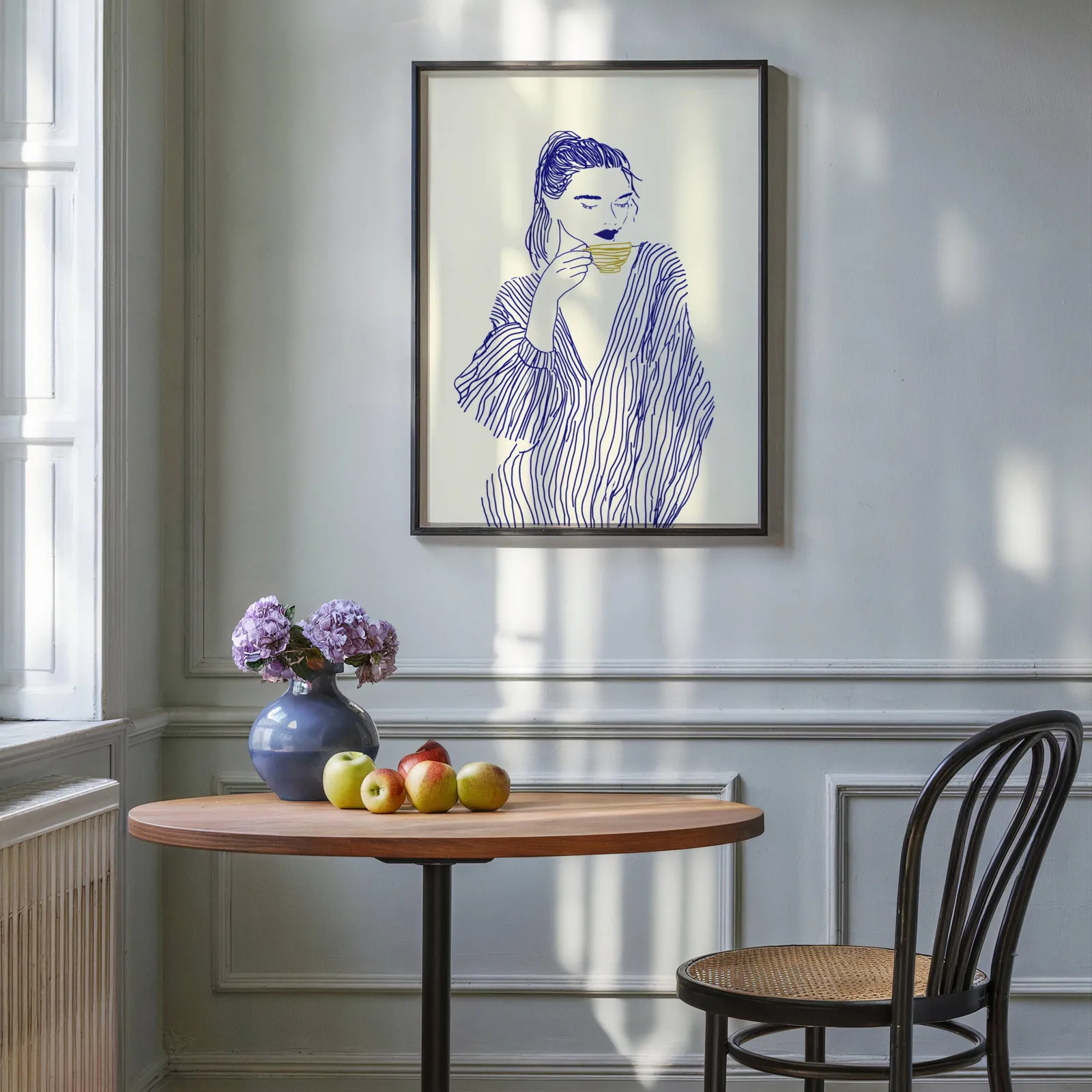 blue line art woman drinking coffee minimalist print, above a round wooden table with apples and a blue vase