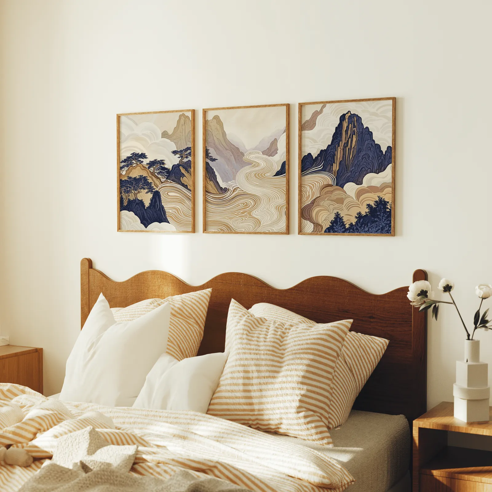 japandi mountain landscape triptych wall art, above a scalloped wooden headboard with striped pillows