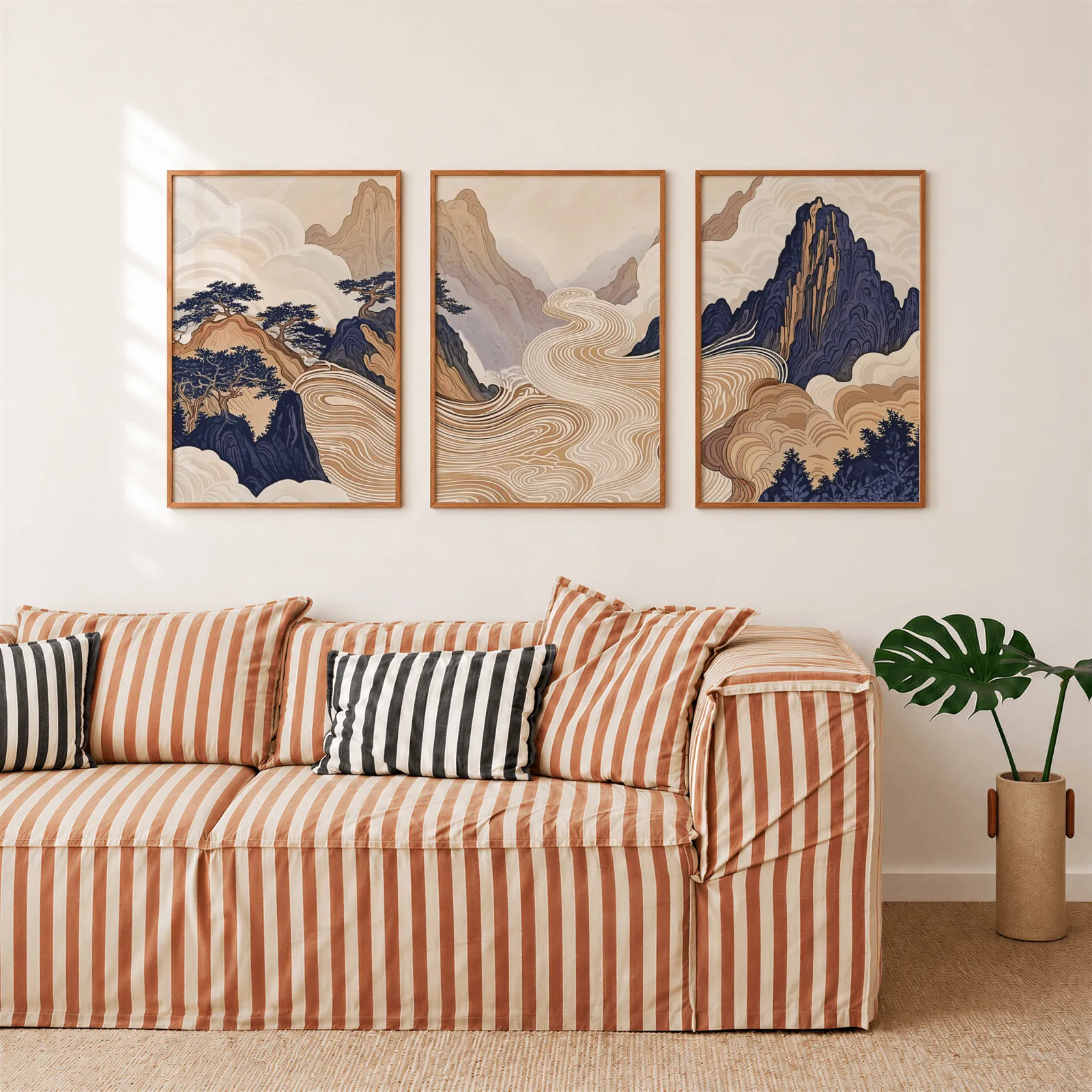 japandi mountain landscape triptych wall art, above a rust-striped sofa beside a potted monstera