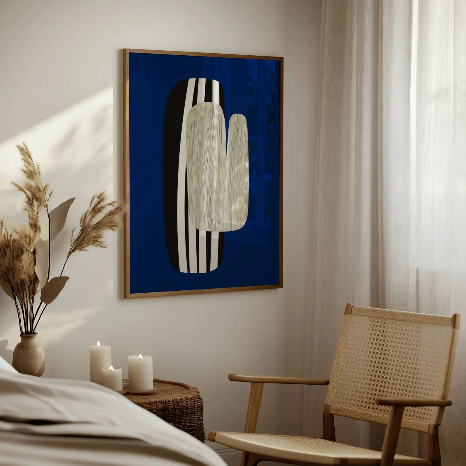 navy blue abstract wall art, above a woven side table with lit candles and pampas grass