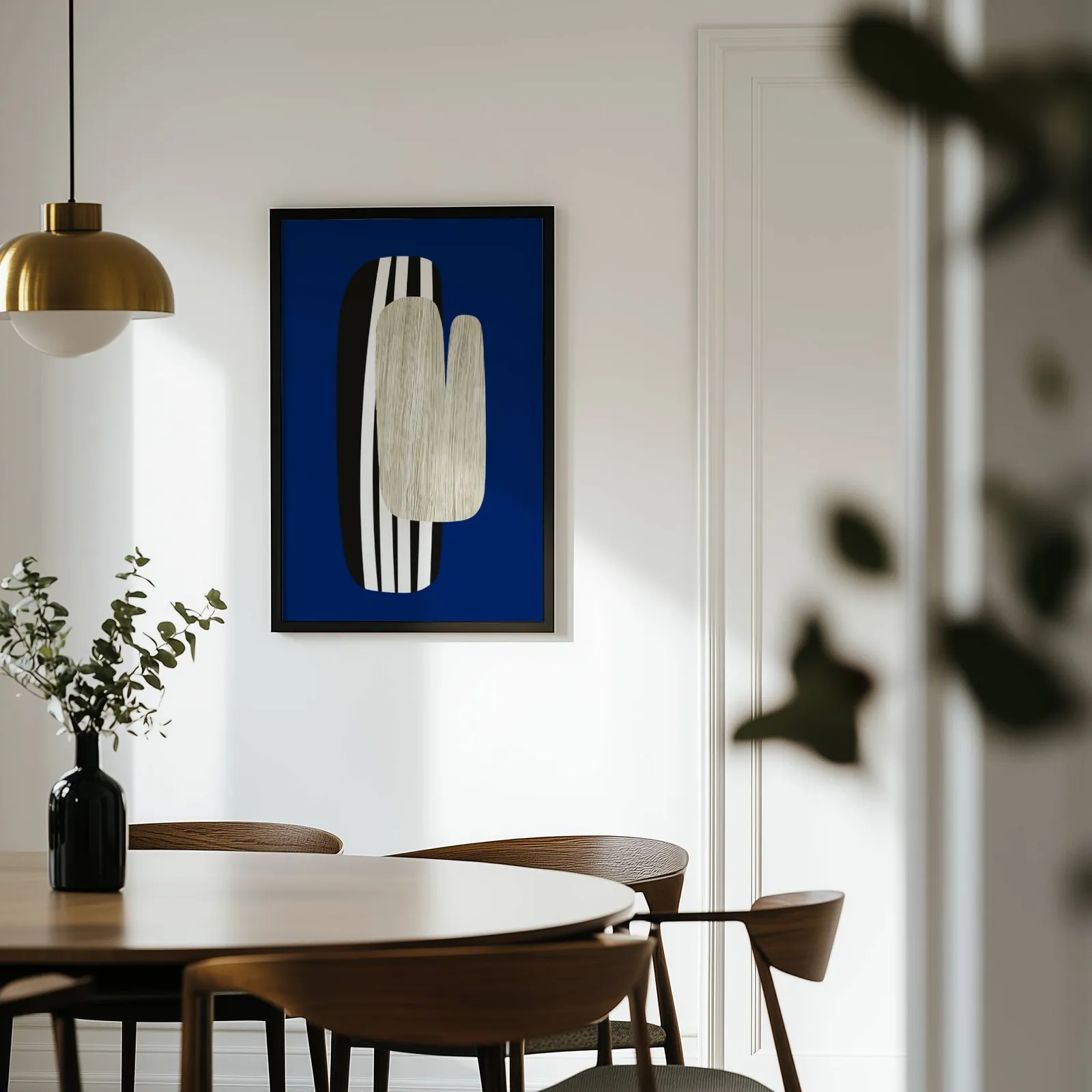 navy blue abstract wall art, on a white wall above a round wooden dining table