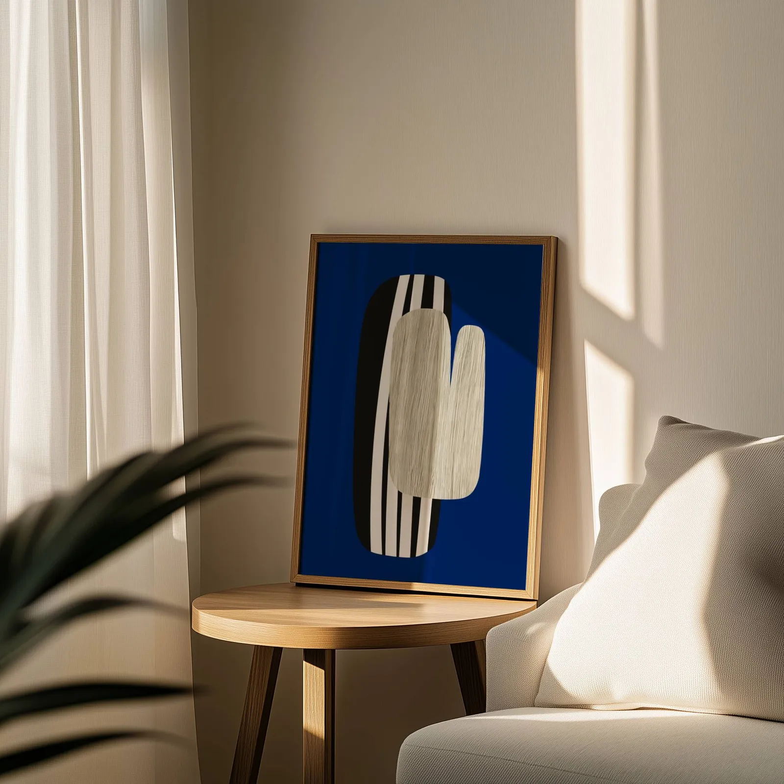 navy blue abstract wall art, leaning on a round wooden side table by a sheer curtain