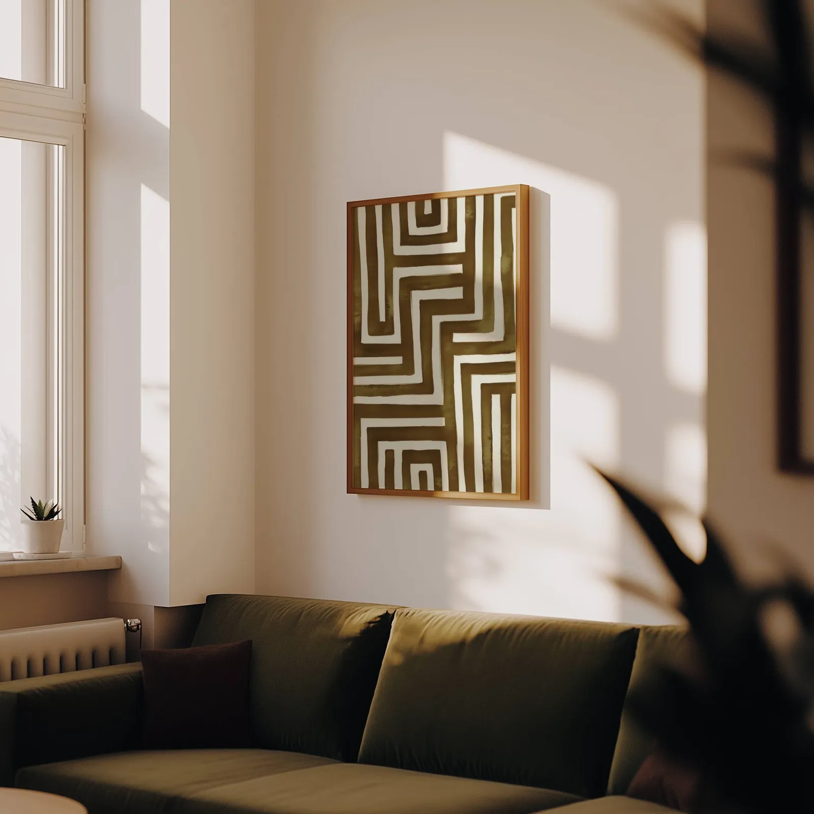 brown abstract maze wall art, above an olive velvet sofa in raking afternoon light