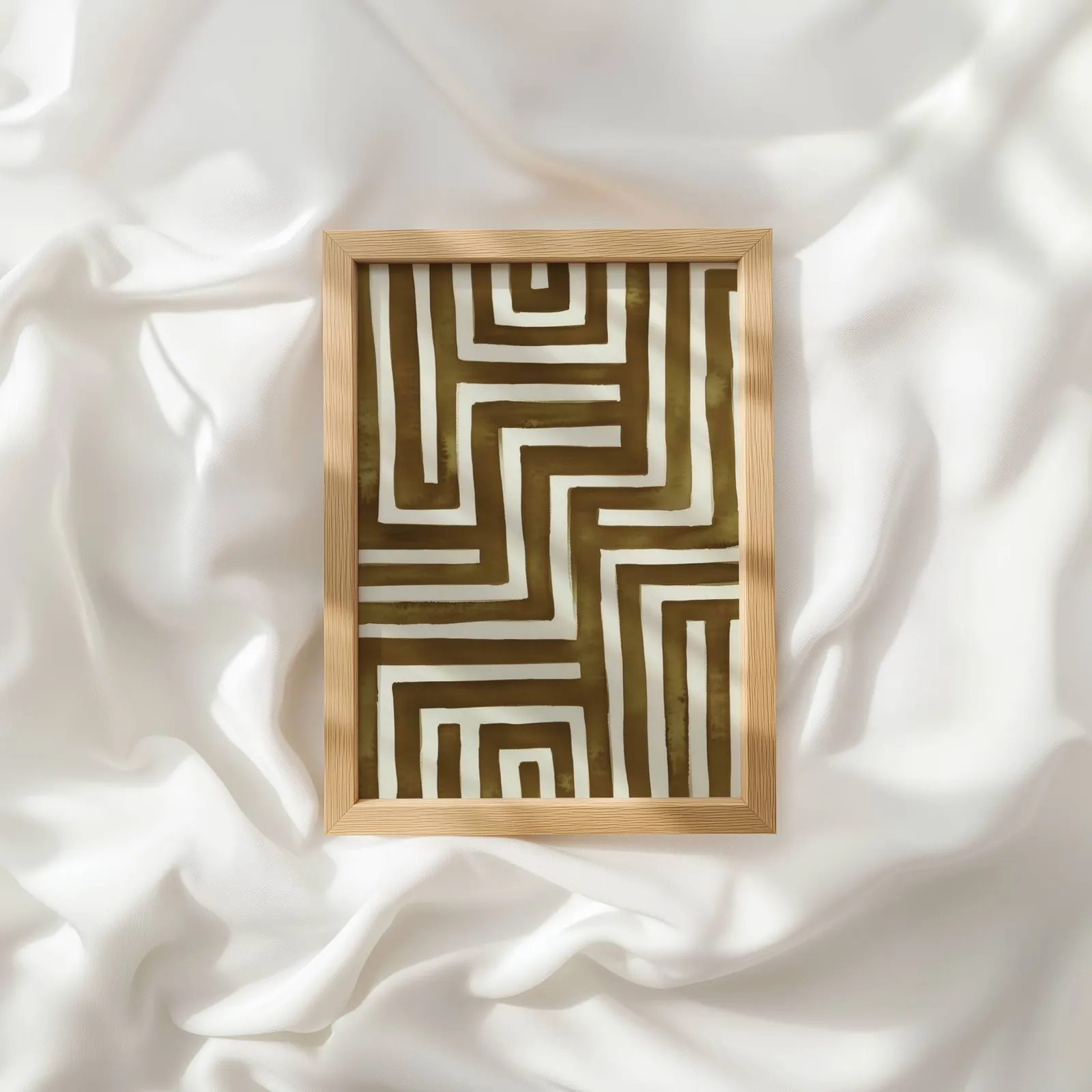 brown abstract maze wall art, resting atop rumpled white silky fabric