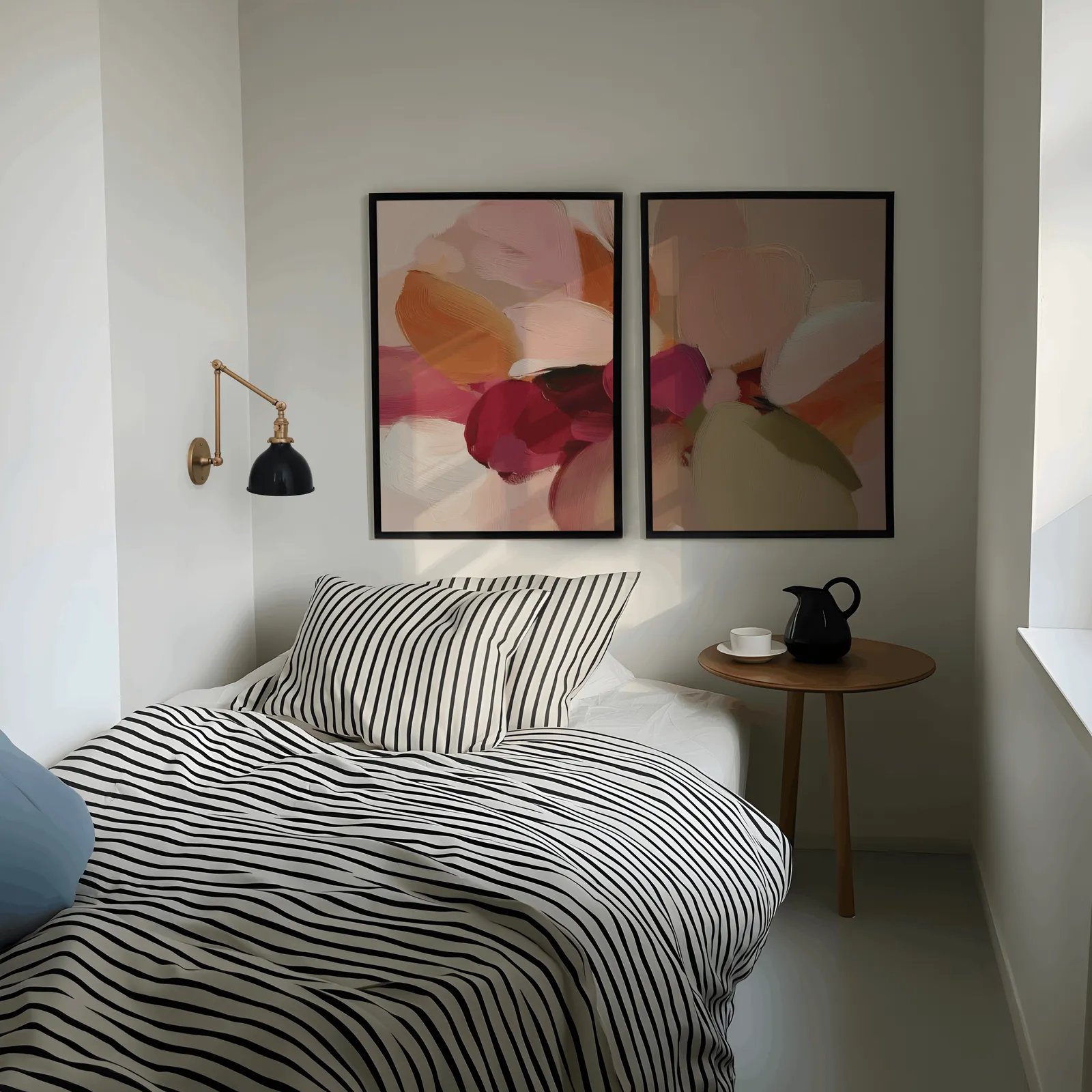 pink and orange abstract floral wall art set of 2, above a striped bed beside a brass swing-arm lamp
