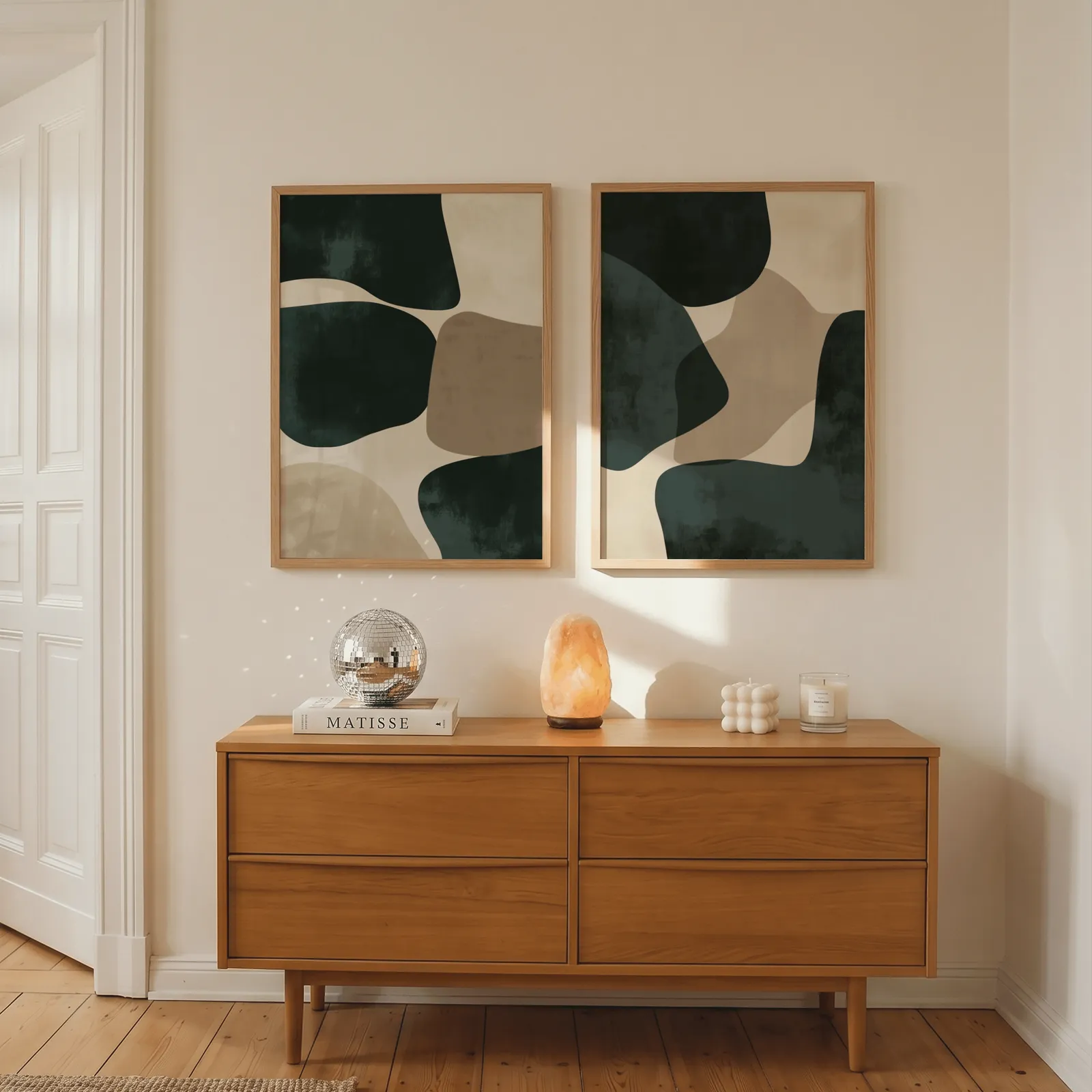 green and beige abstract wall art set of two, above a wooden dresser with a salt lamp and disco ball