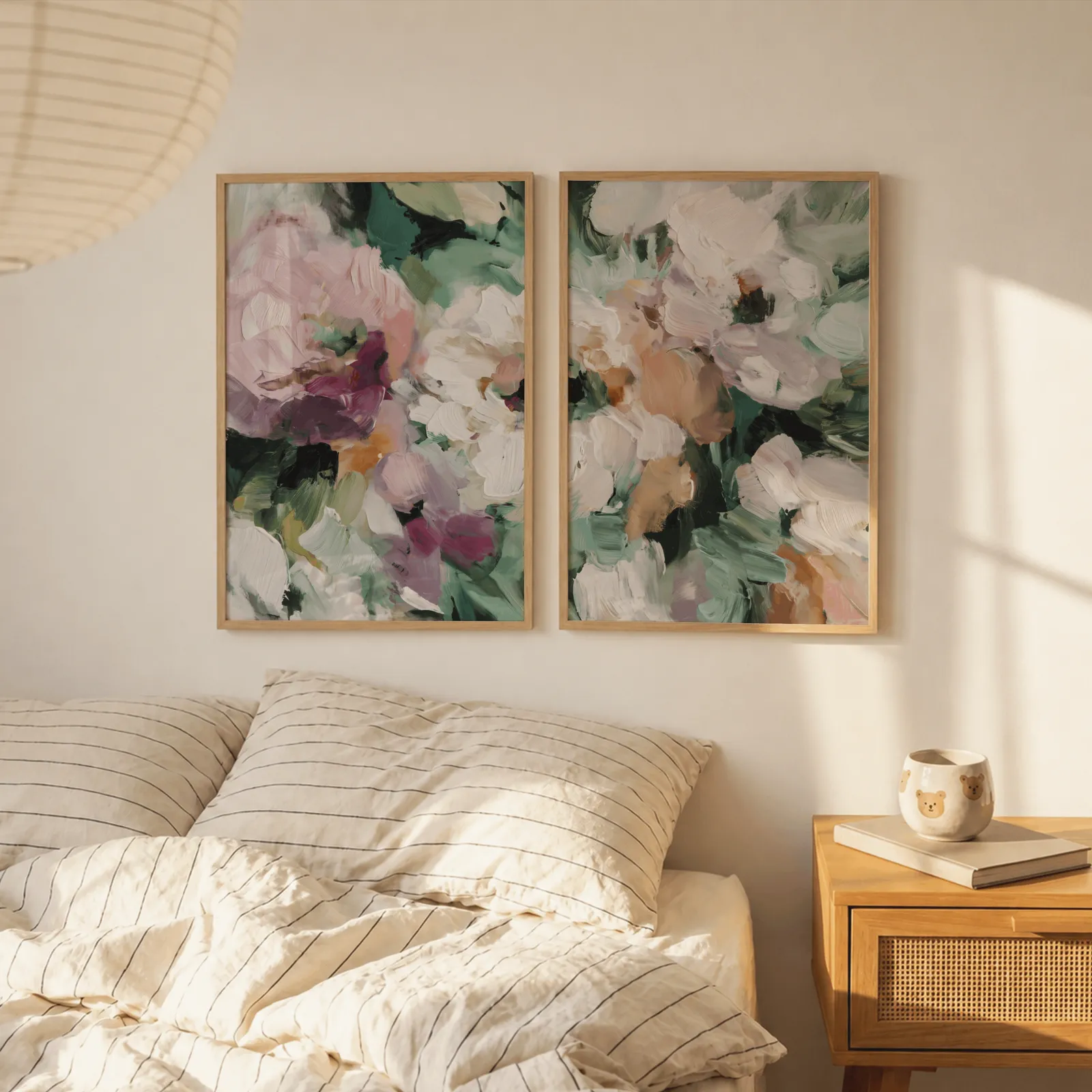 pink and green abstract floral wall art set of two, above a striped linen bed beside a paper lantern shade