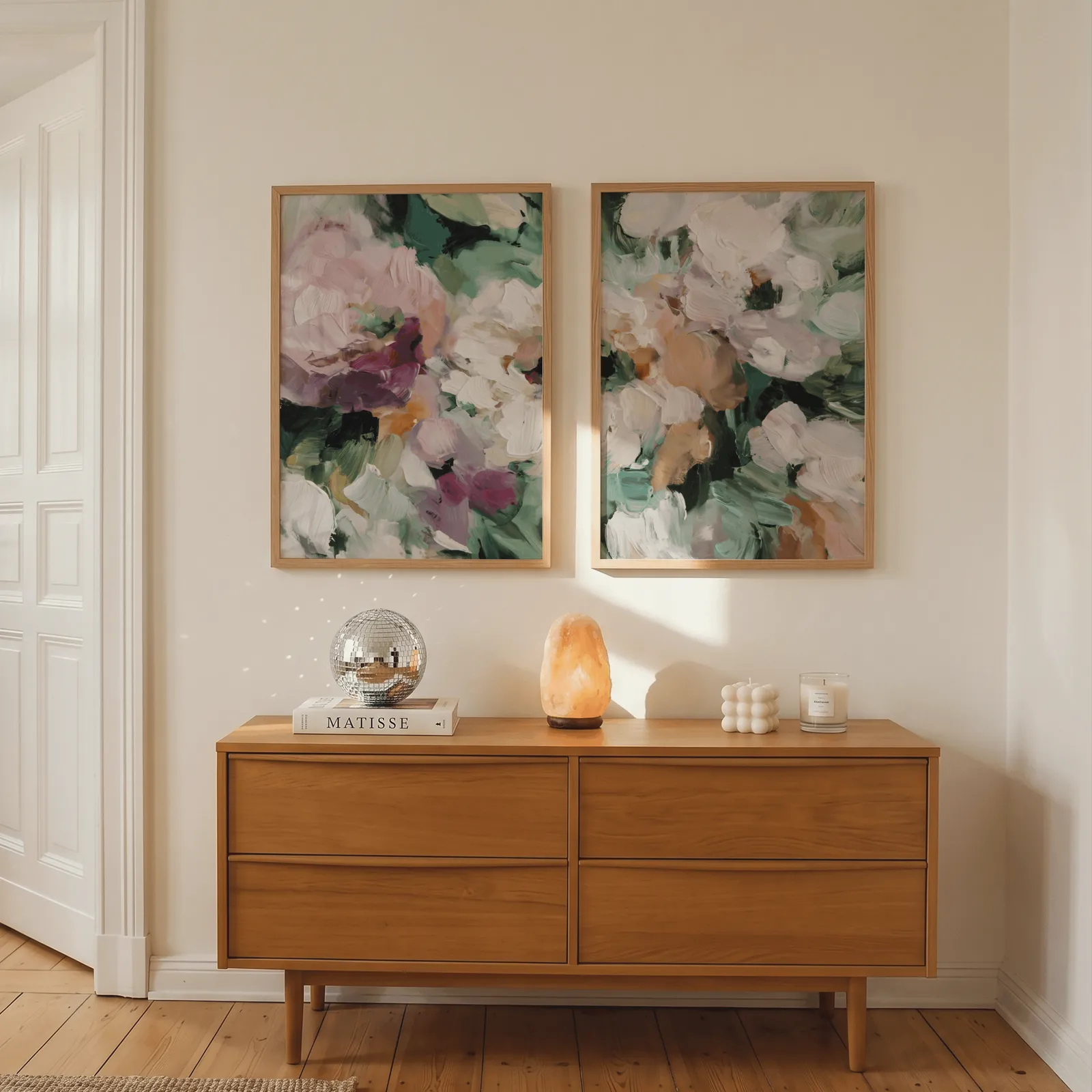 pink and green abstract floral wall art set of two, above a wooden dresser with a salt lamp and disco ball