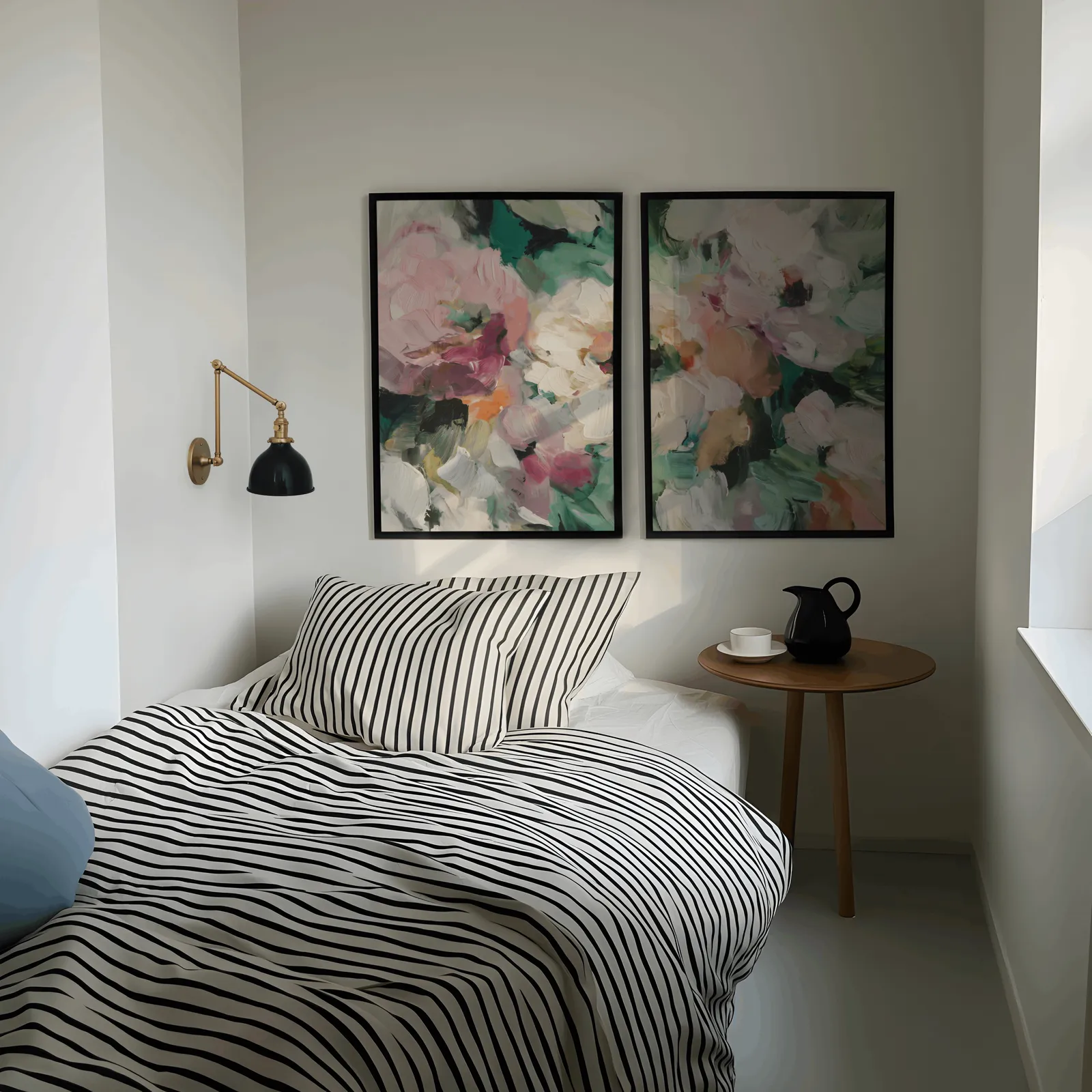 pink and green abstract floral wall art set of two, above a striped bed beside a brass swing-arm lamp