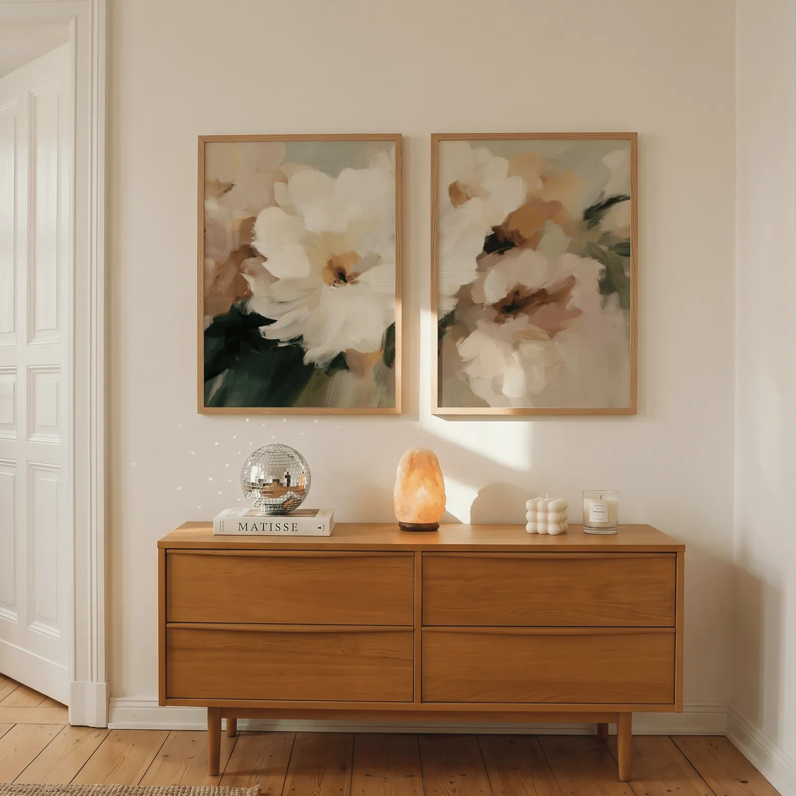 pink and cream floral wall art set of two, above a wooden dresser with a salt lamp and disco ball