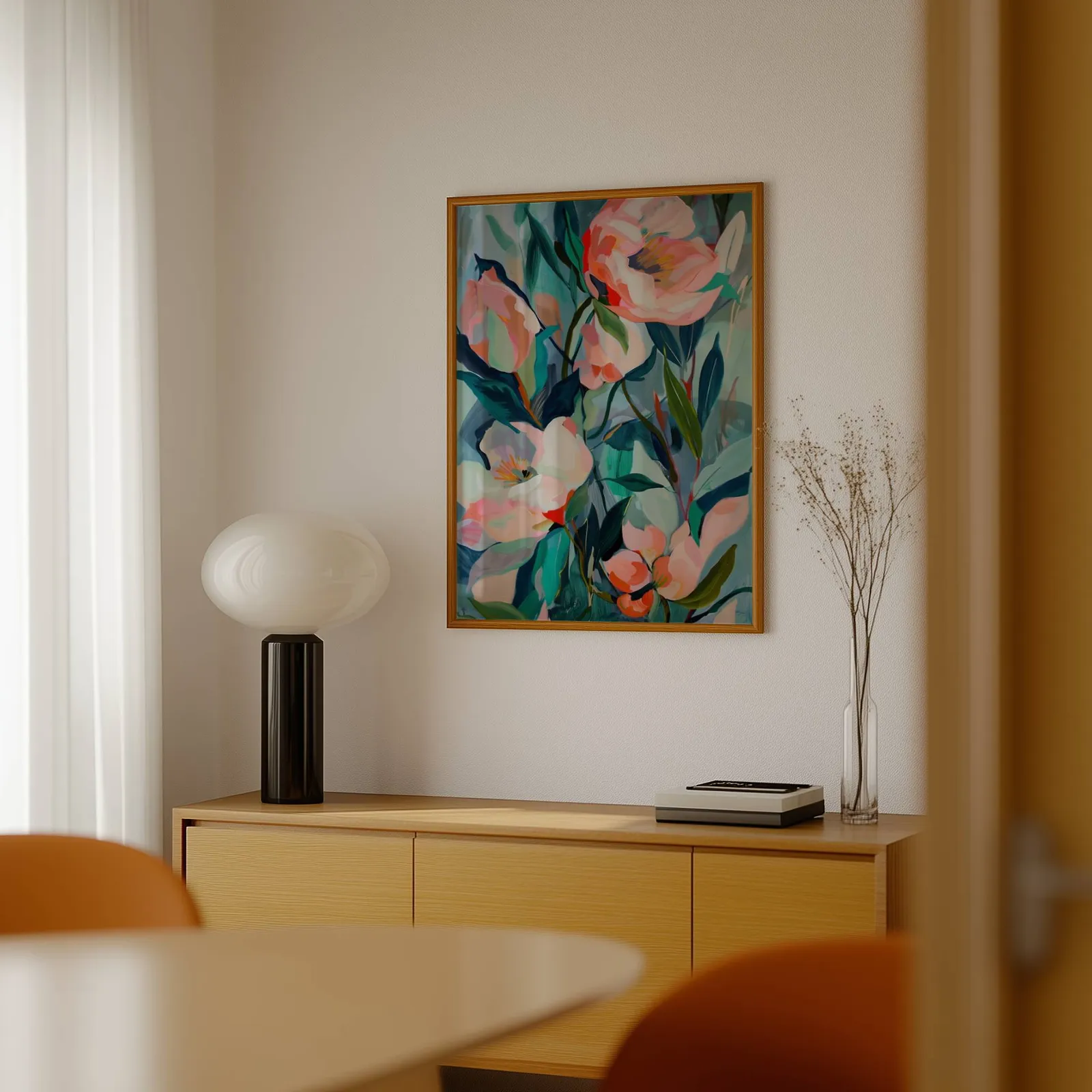 pink floral botanical wall art, above a light wood sideboard beside a bulbous black lamp