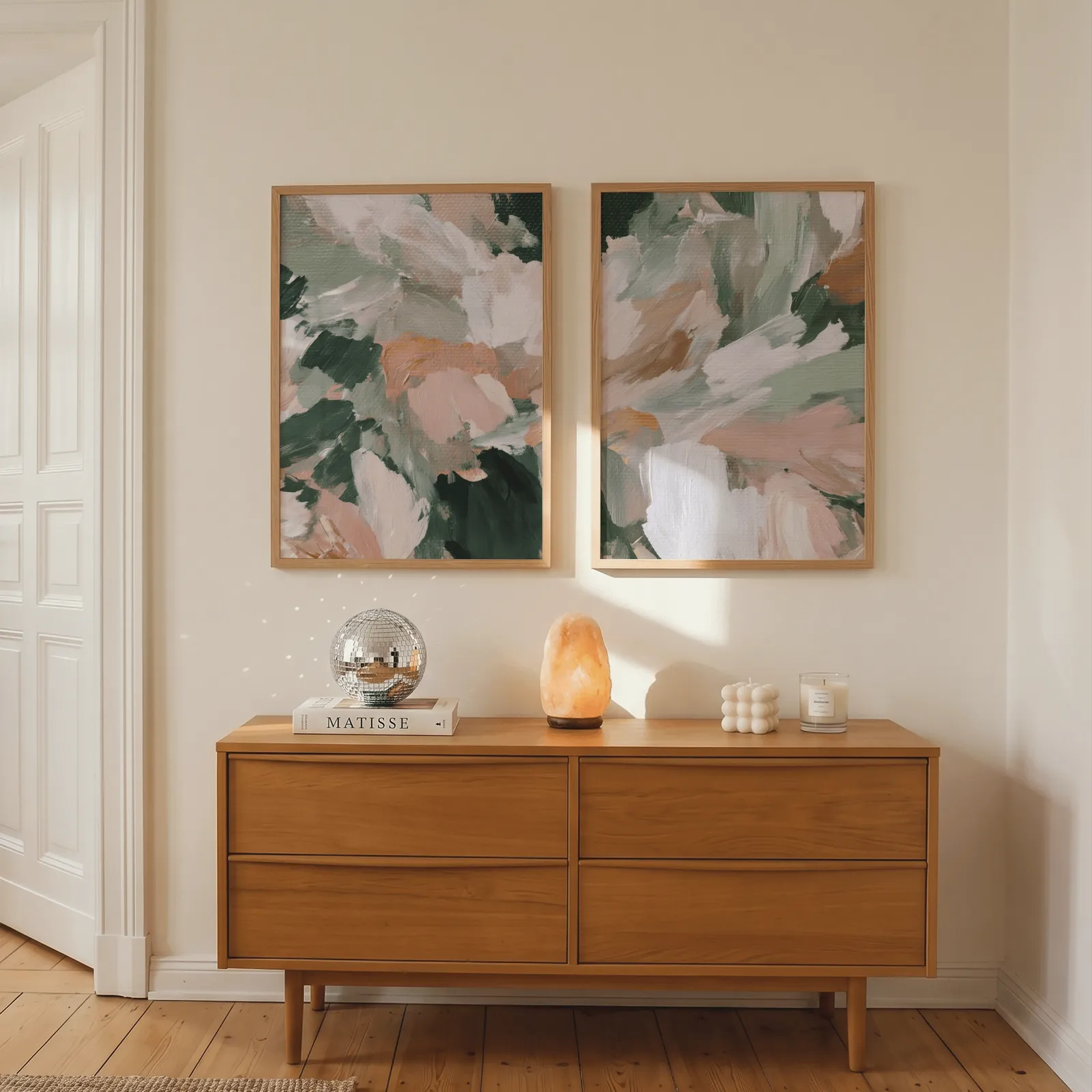 pink and green abstract floral wall art set of two, above a wooden dresser with a salt lamp and disco ball