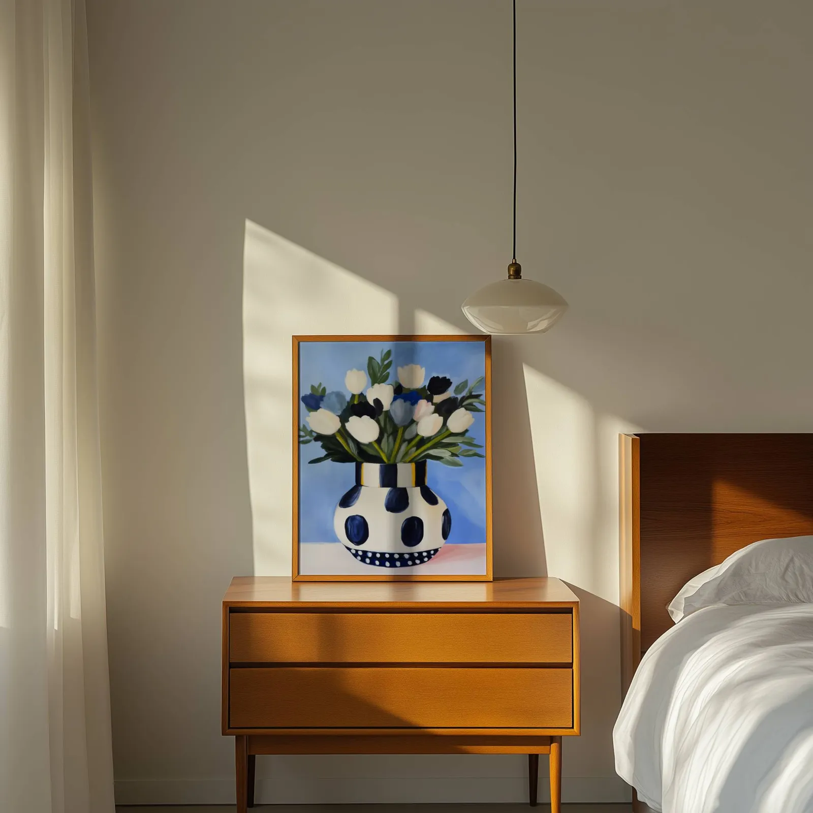 blue floral wall art with polka dot vase, propped on a wooden dresser beside a pendant lamp