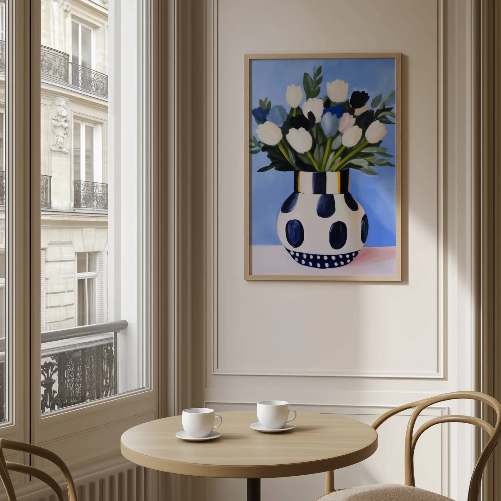 blue floral wall art with polka dot vase, above a round café table set with two coffee cups