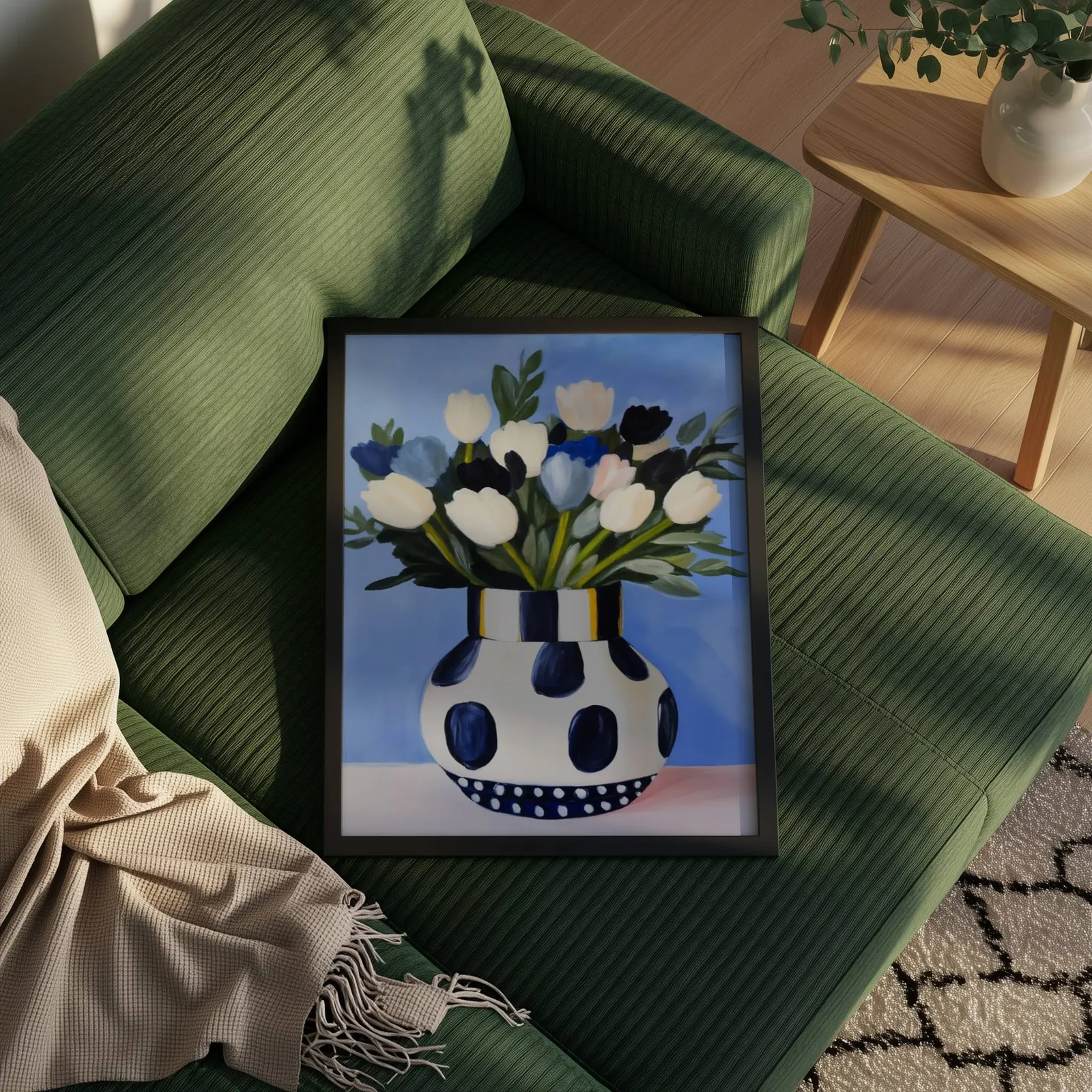 blue floral wall art with polka dot vase, propped on a ribbed olive-green sofa beside a fringed throw