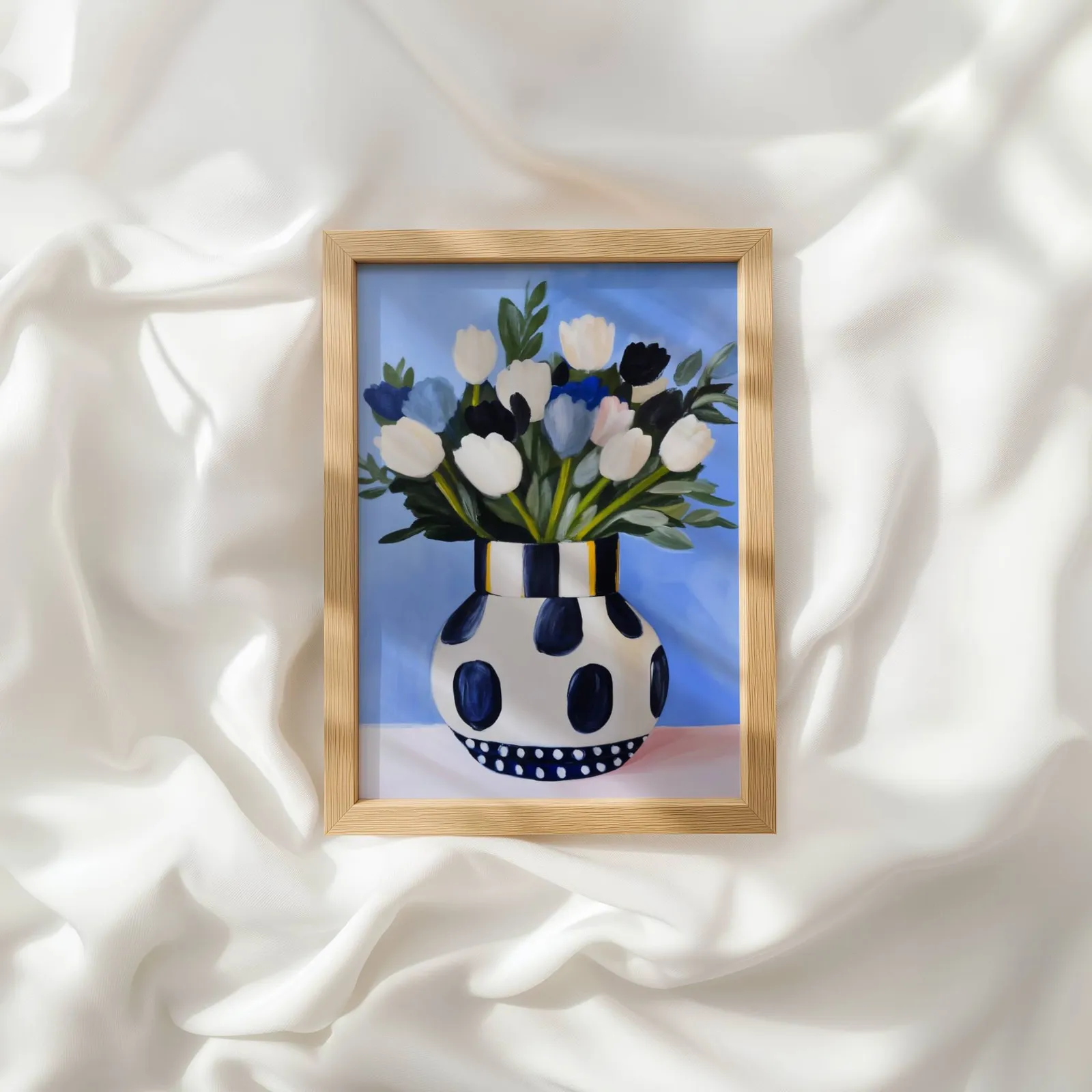 blue floral wall art with polka dot vase, resting atop rumpled white silky fabric