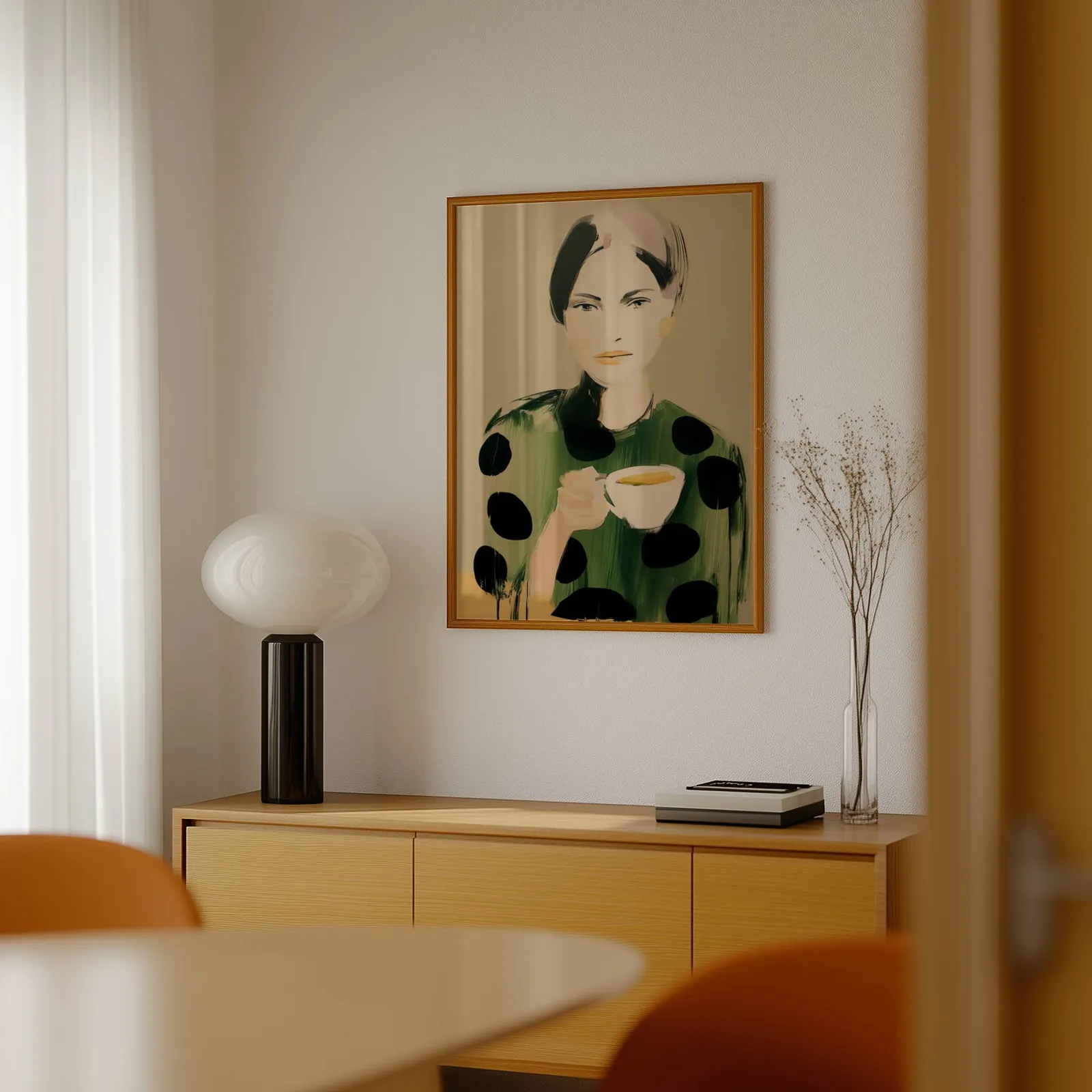 green polka dot portrait wall art woman with teacup, above a light wood sideboard beside a bulbous black lamp