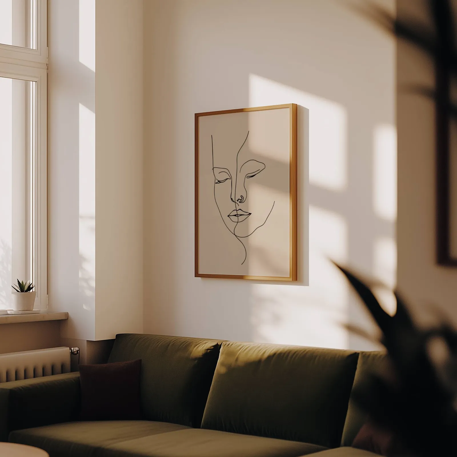 beige abstract face line art wall art, above an olive velvet sofa in raking afternoon light