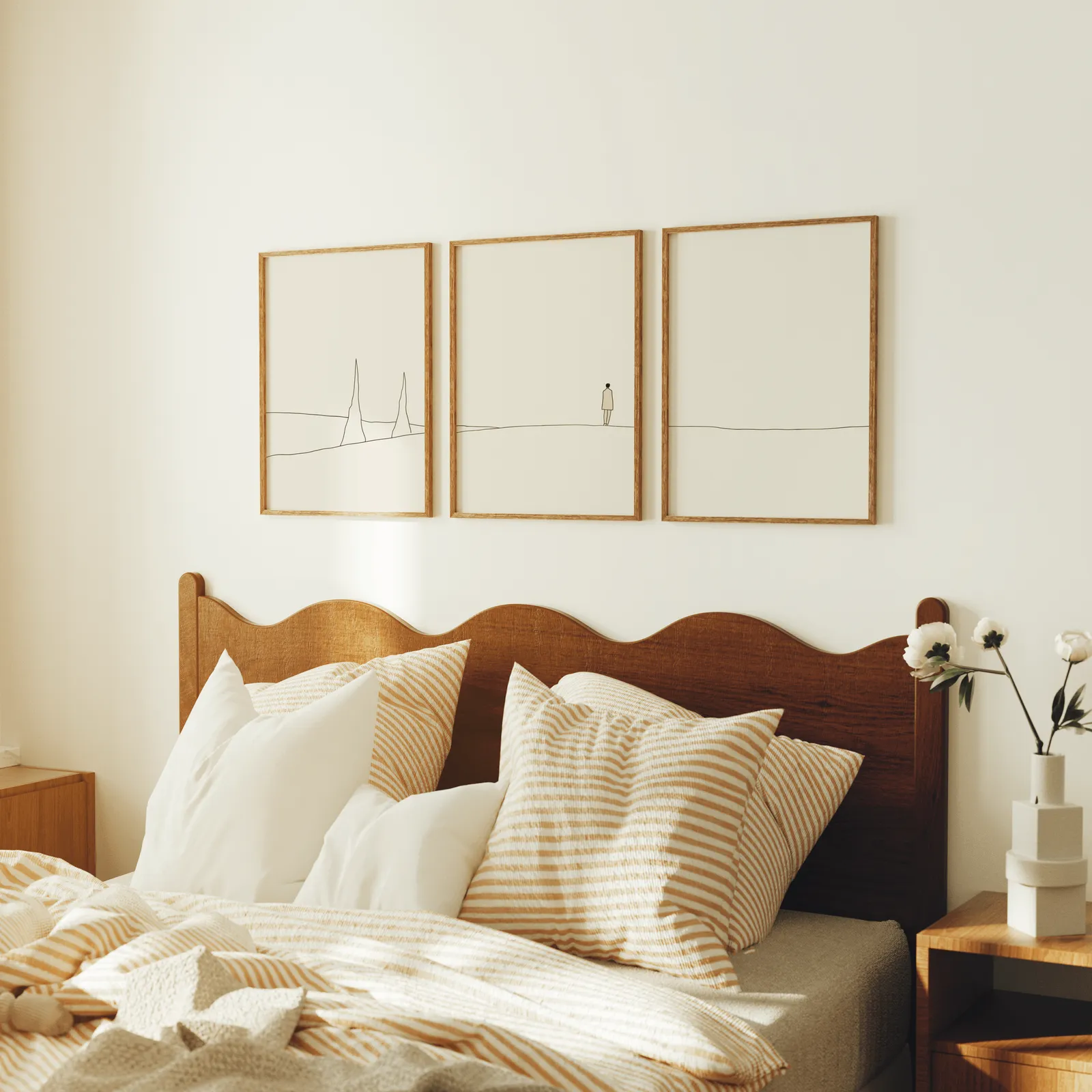 minimalist landscape wall art set of 3 with figure and horizon line, above a scalloped wooden headboard with striped pillows