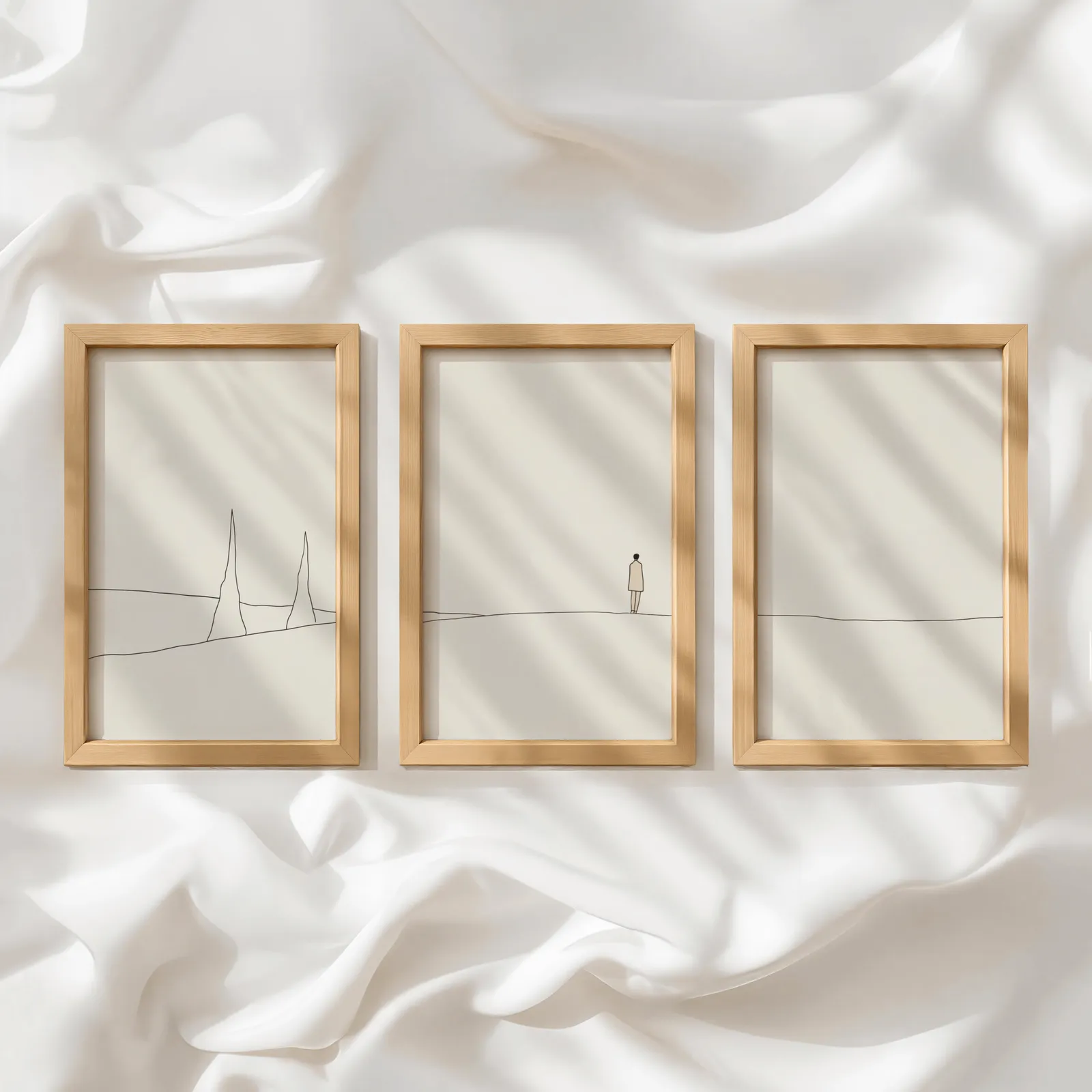 minimalist landscape wall art set of 3 with figure and horizon line, in a row atop rumpled white silky fabric