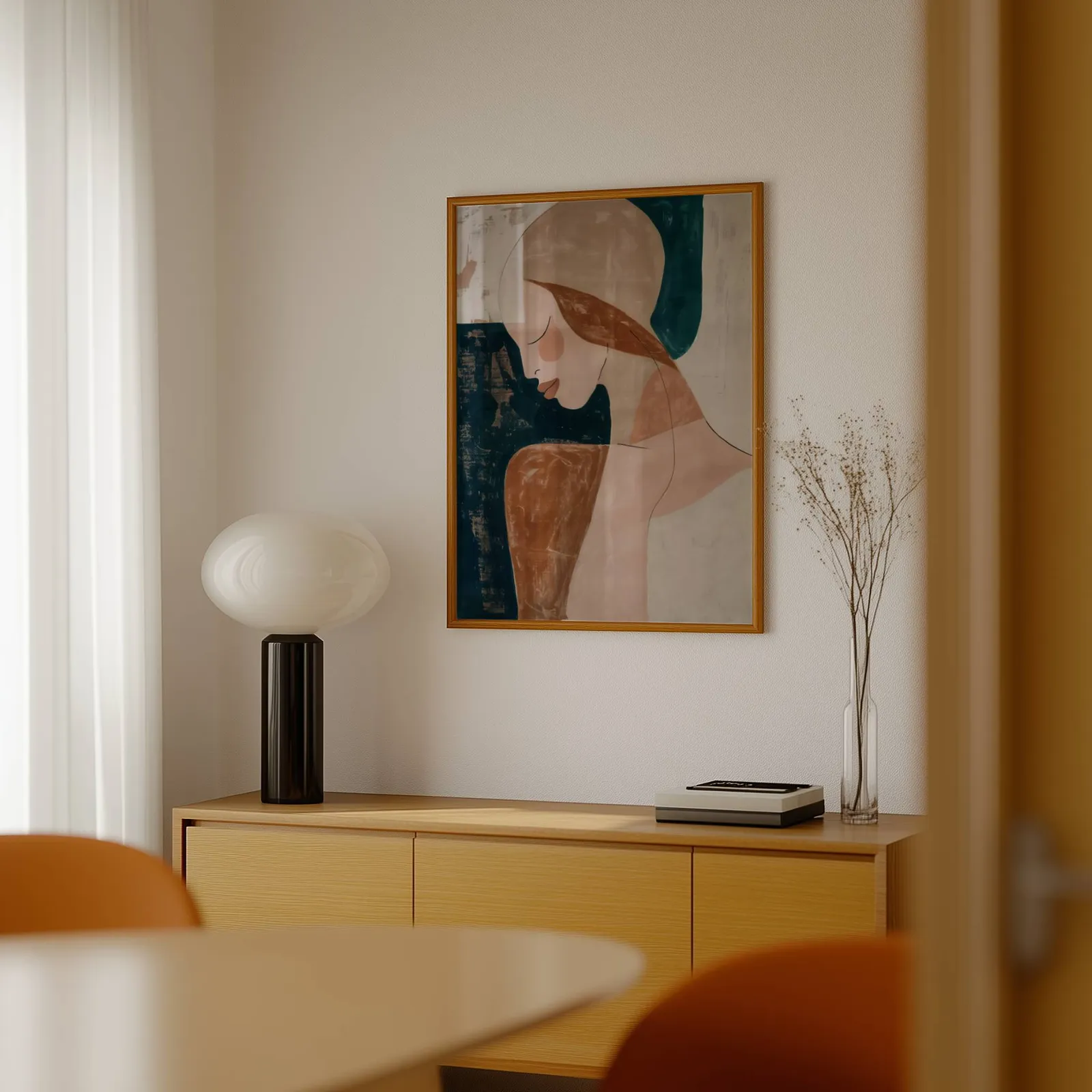 abstract terracotta woman portrait wall art, above a light wood sideboard beside a bulbous black lamp