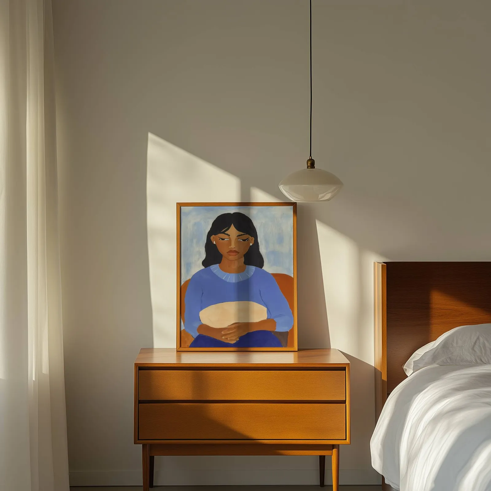 blue portrait wall art of seated woman, propped on a wooden dresser beside a pendant lamp