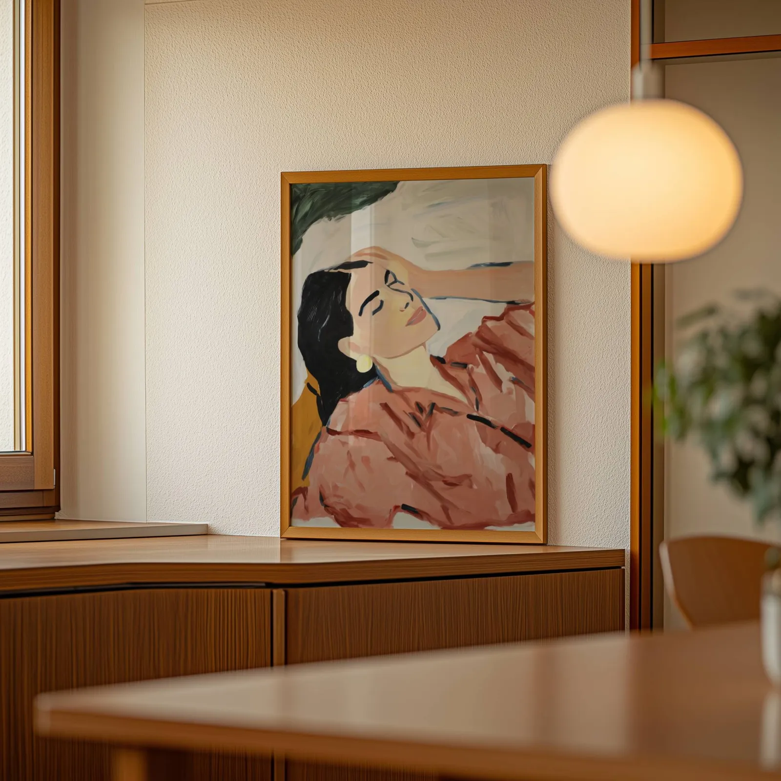 terracotta abstract woman wall art, leaning on a wooden sideboard beside a glowing globe pendant