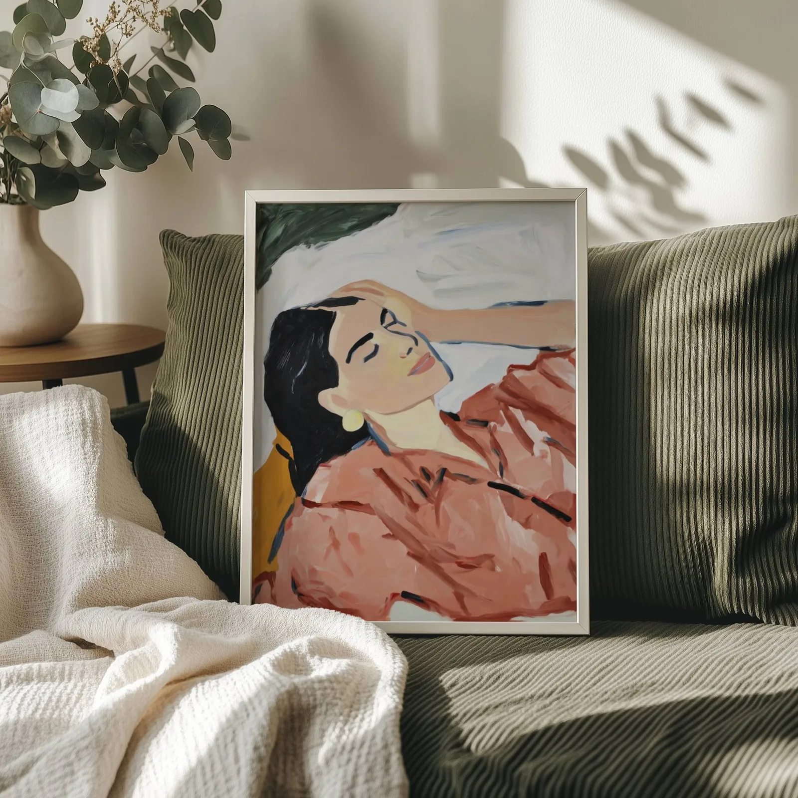terracotta abstract woman wall art, propped on an olive corduroy sofa beside a eucalyptus vase