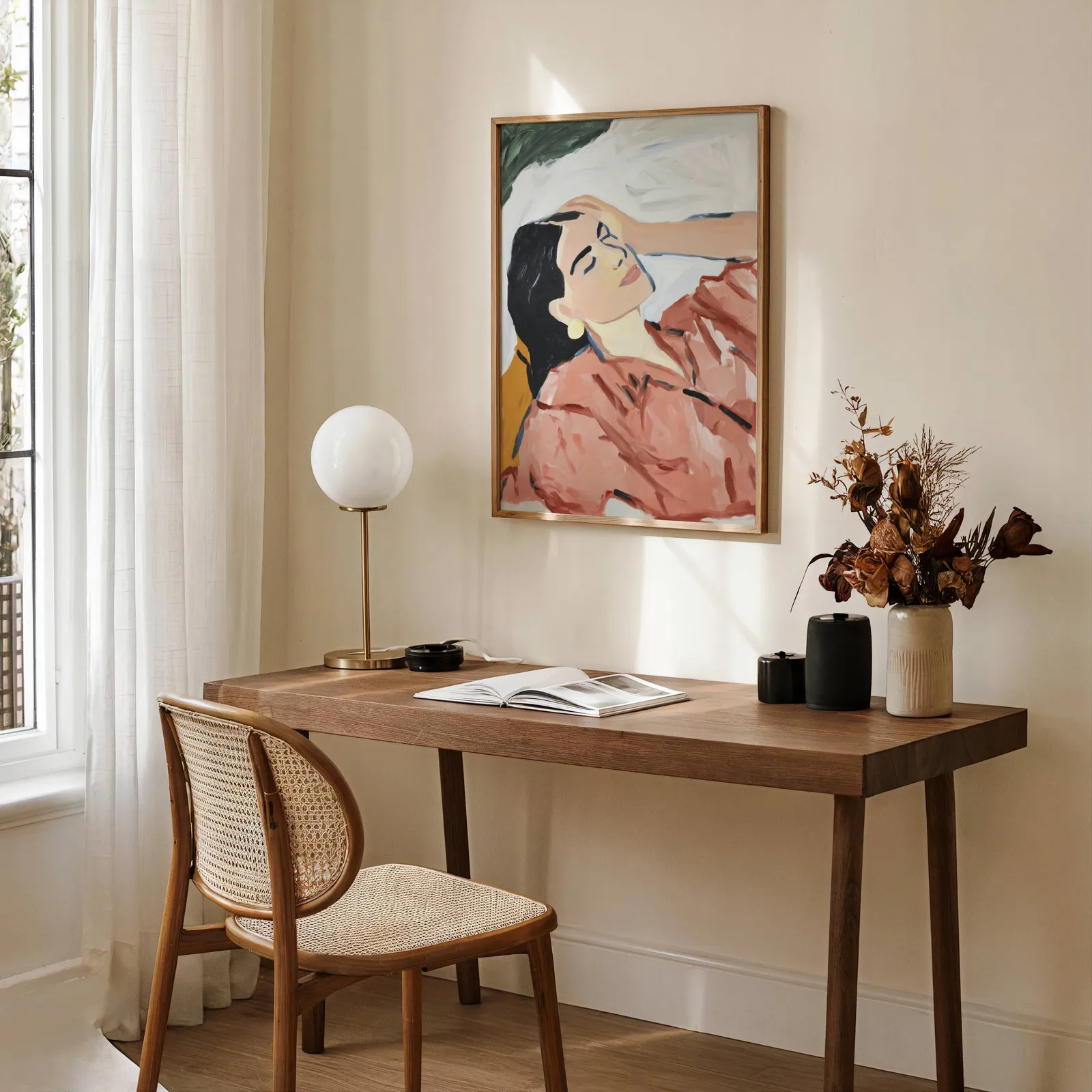 terracotta abstract woman wall art, above a wooden desk with a globe lamp and dried flowers