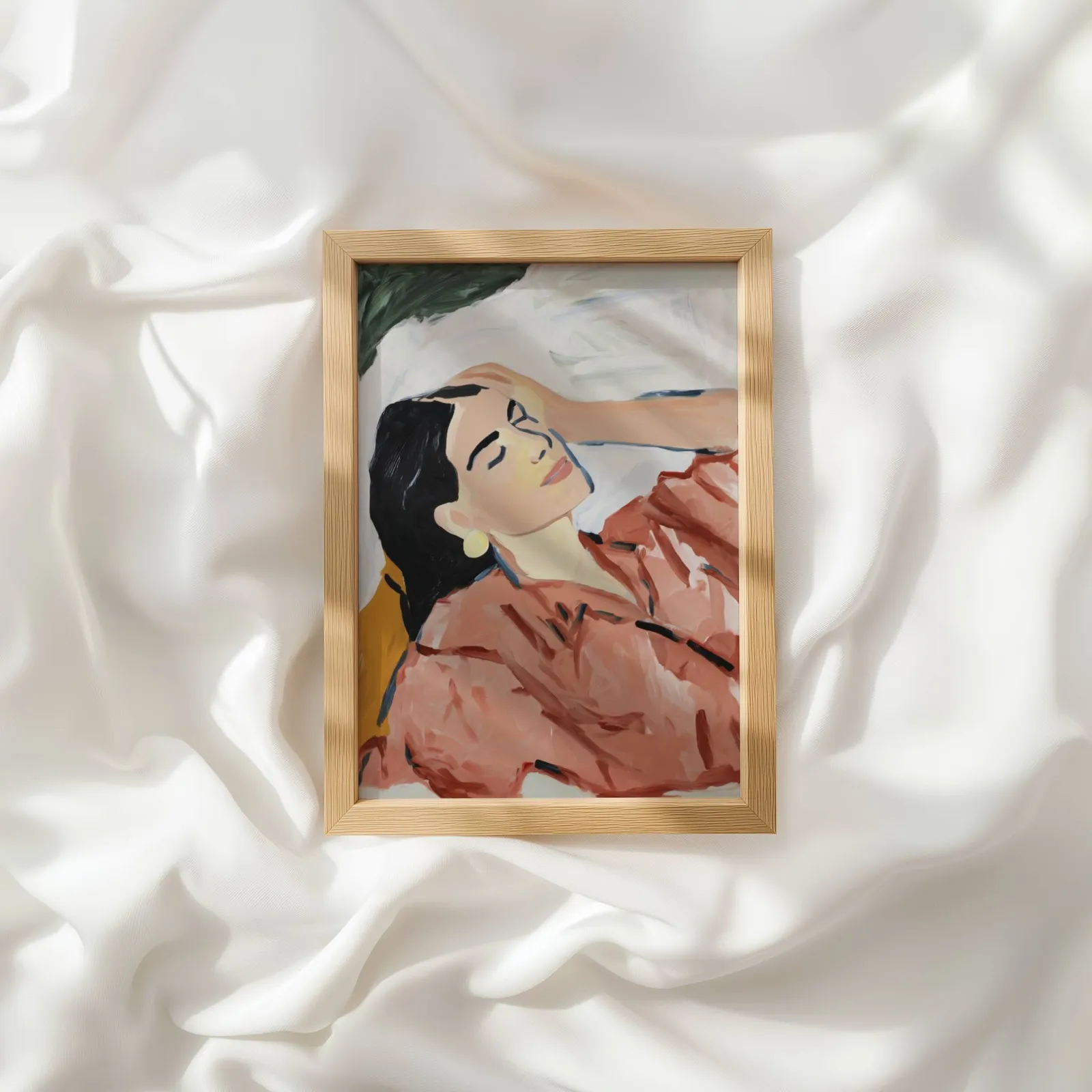 terracotta abstract woman wall art, resting atop rumpled white silky fabric