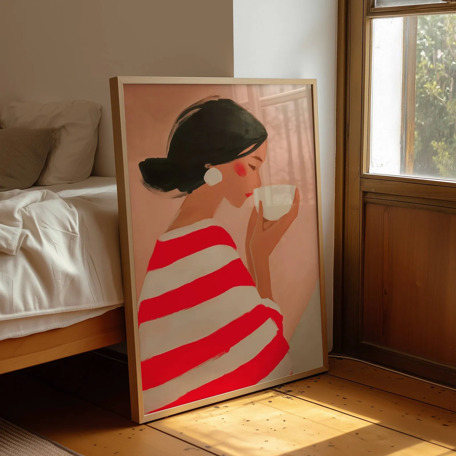 woman drinking coffee in red striped top wall art, leaning by a sunlit window beside an unmade bed