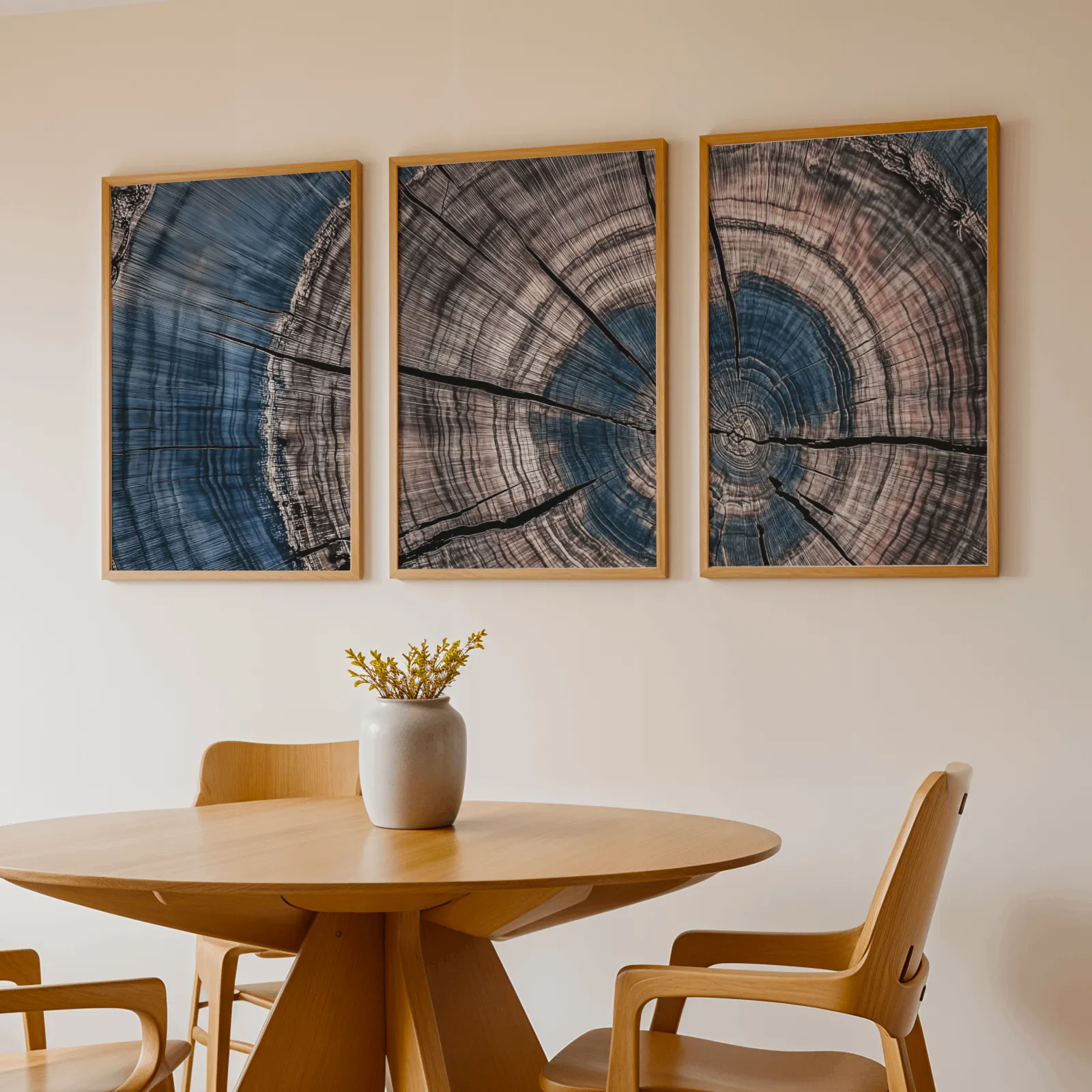 blue and pink tree rings triptych wall art, above a round wooden table with a stoneware vase
