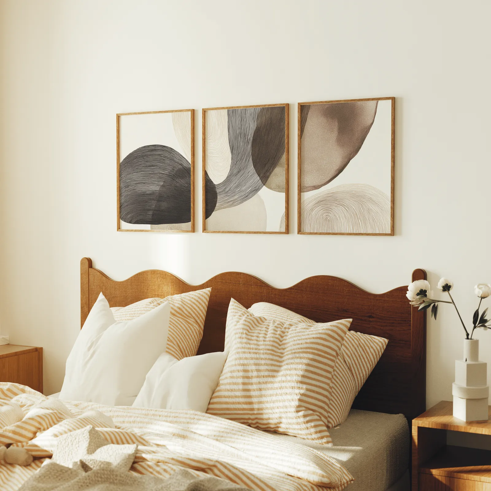 neutral abstract wall art set of 3 with curved organic forms, above a scalloped wooden headboard with striped pillows