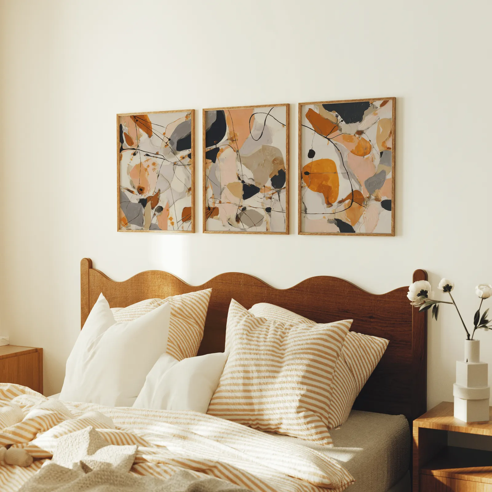 orange abstract triptych wall art set, above a scalloped wooden headboard with striped pillows