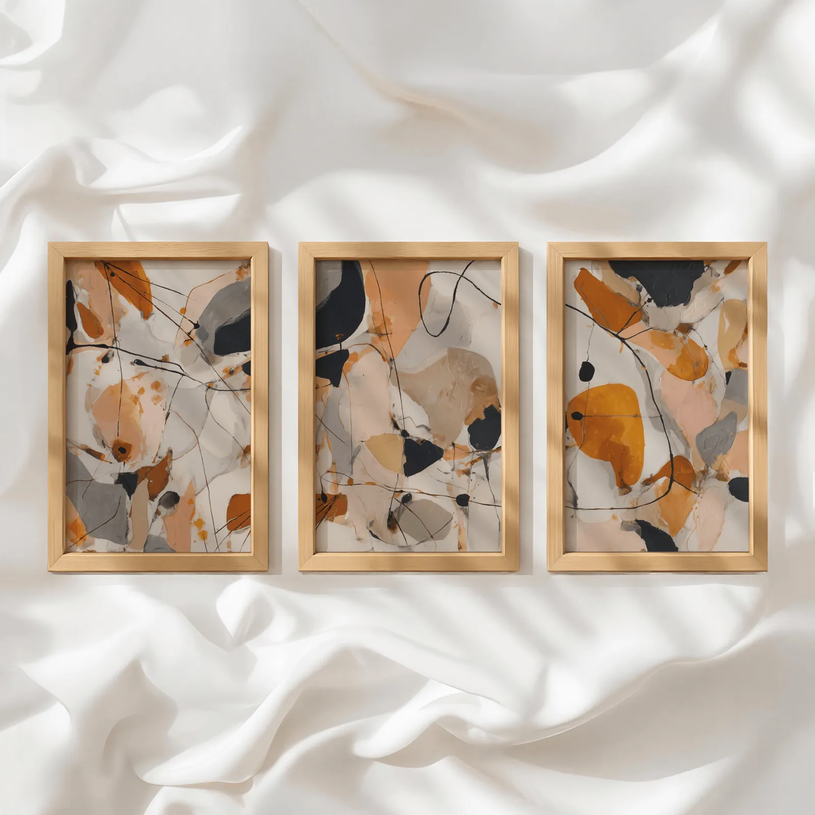 orange abstract triptych wall art set, in a row atop rumpled white silky fabric