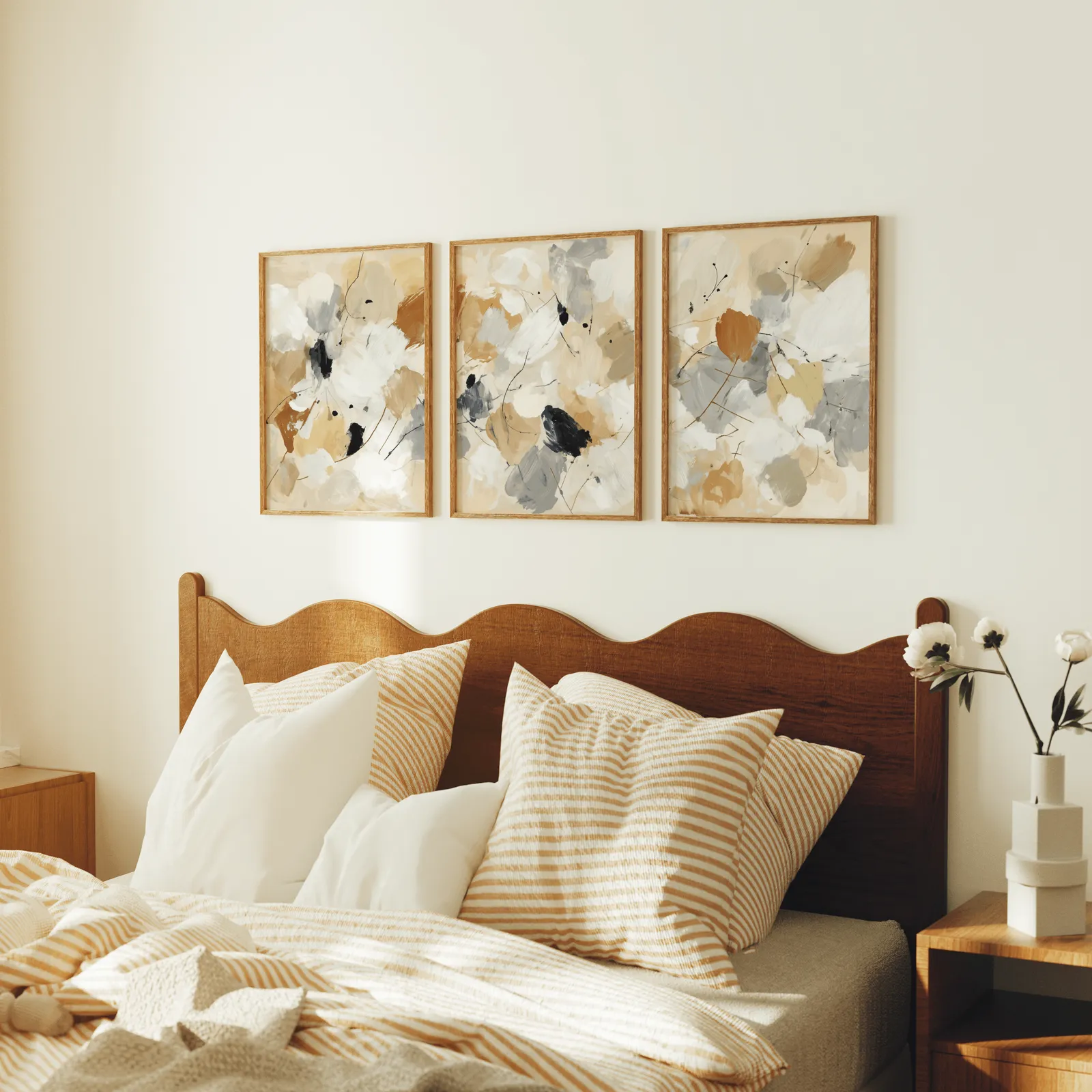 neutral abstract triptych wall art, above a scalloped wooden headboard with striped pillows