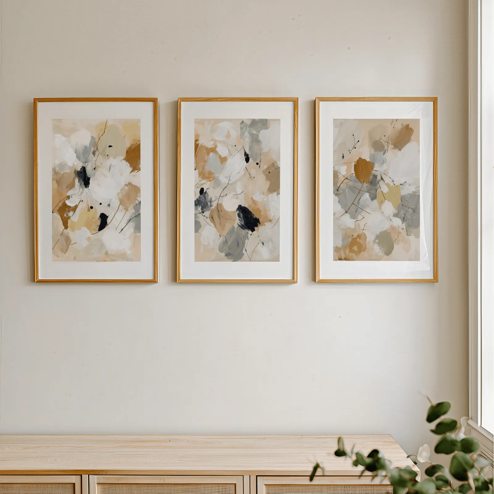 neutral abstract triptych wall art, in a row above a light wooden sideboard near a window