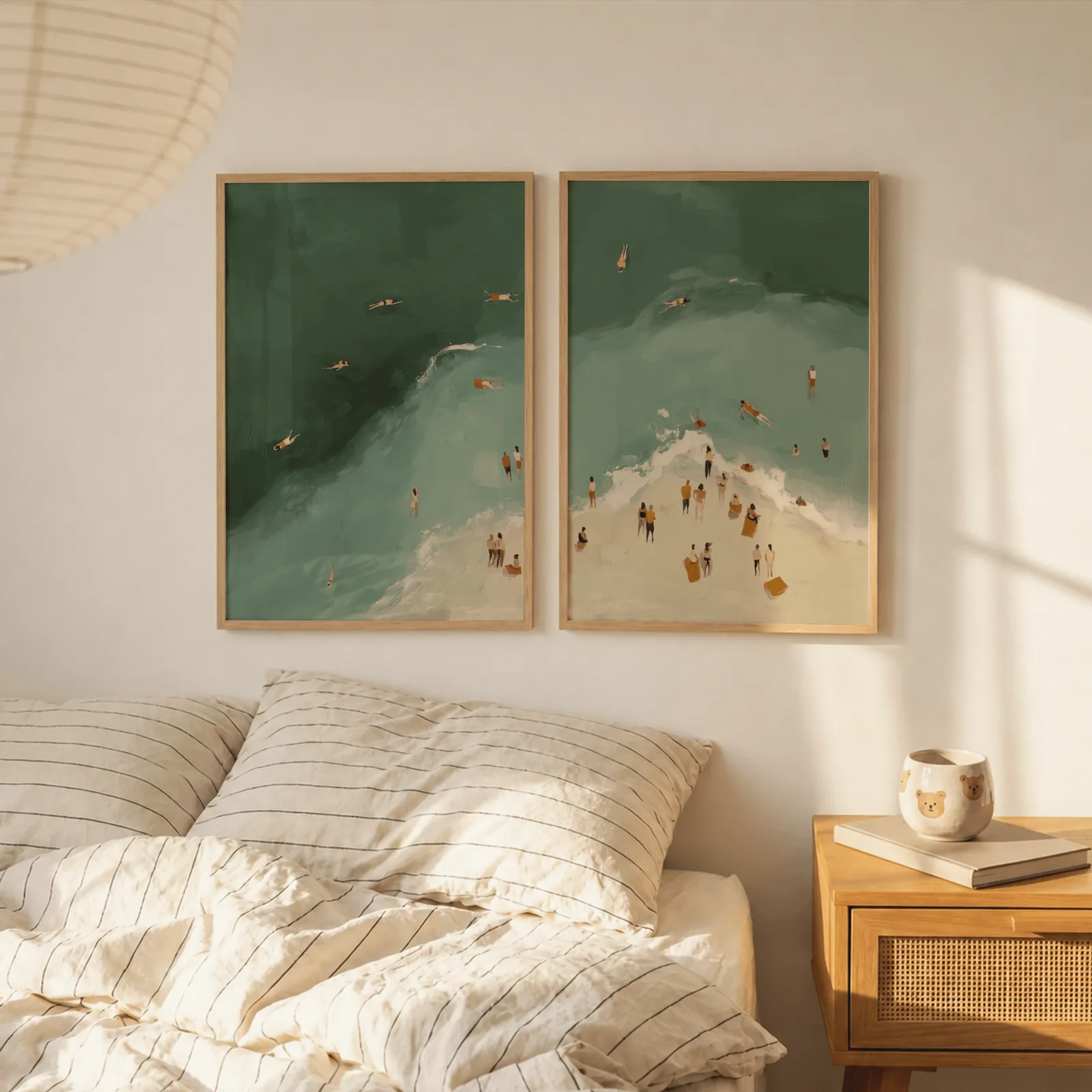 green coastal beach wall art set of two with swimmers, above a striped linen bed beside a paper lantern shade