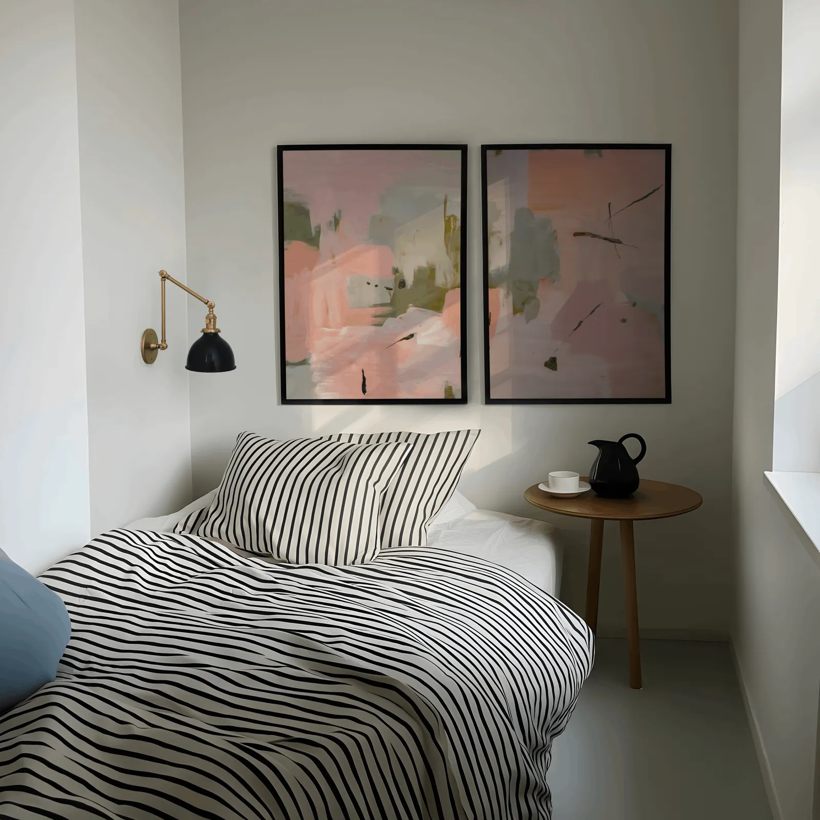 pink and green abstract wall art set of two, above a striped bed beside a brass swing-arm lamp
