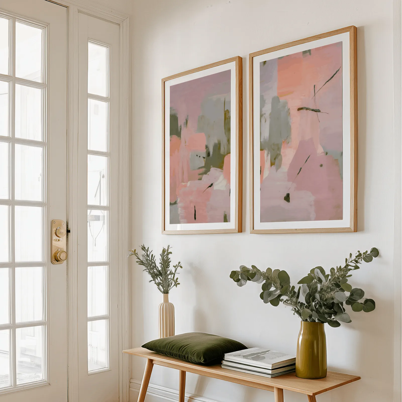 pink and green abstract wall art set of two, above a wooden bench with eucalyptus stems and a green cushion