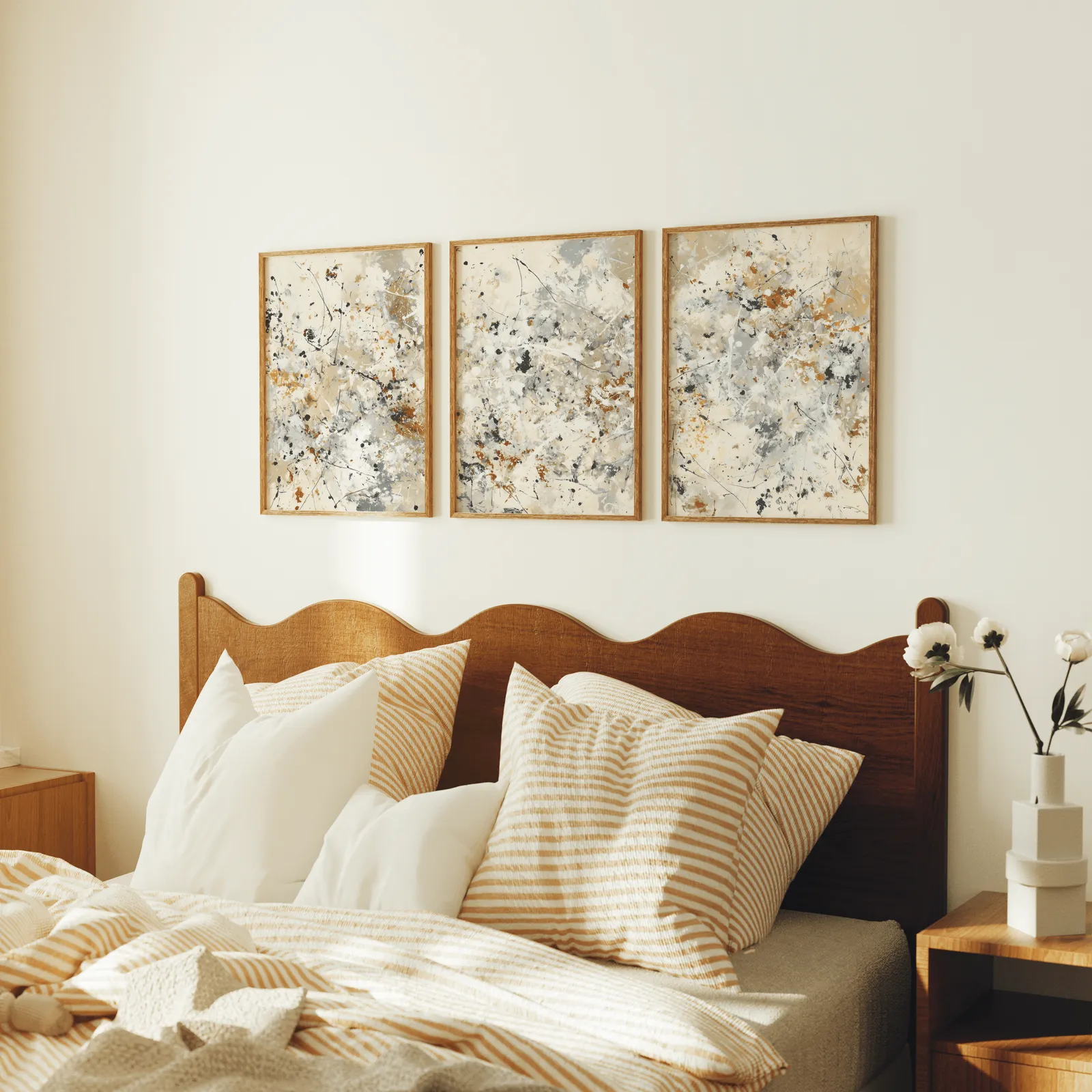 neutral abstract splatter wall art set of three, above a scalloped wooden headboard with striped pillows